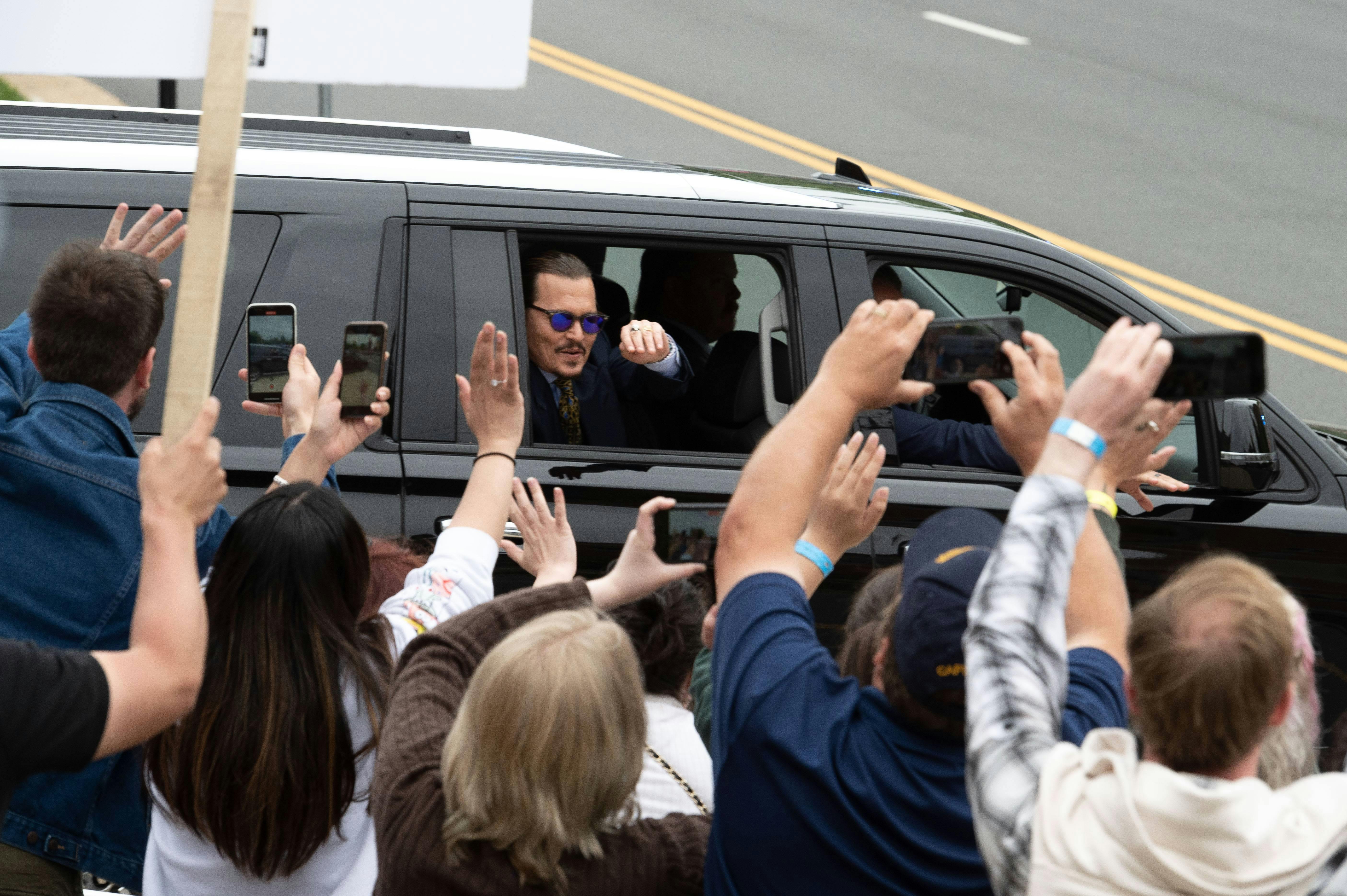 Depp vinker til de fremmødte fans foran retten i Fairfax, Virginia.&nbsp;
