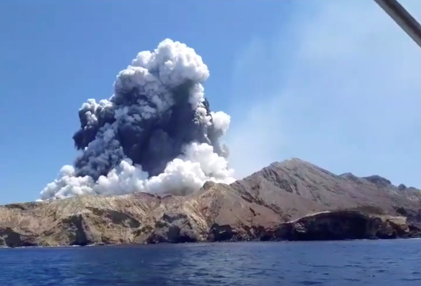Turister på en nærliggende båd fotograferede øjeblikket, hvor vulkanen gik i udbrud og spyede store mængder brændende sten og aske i luften.
