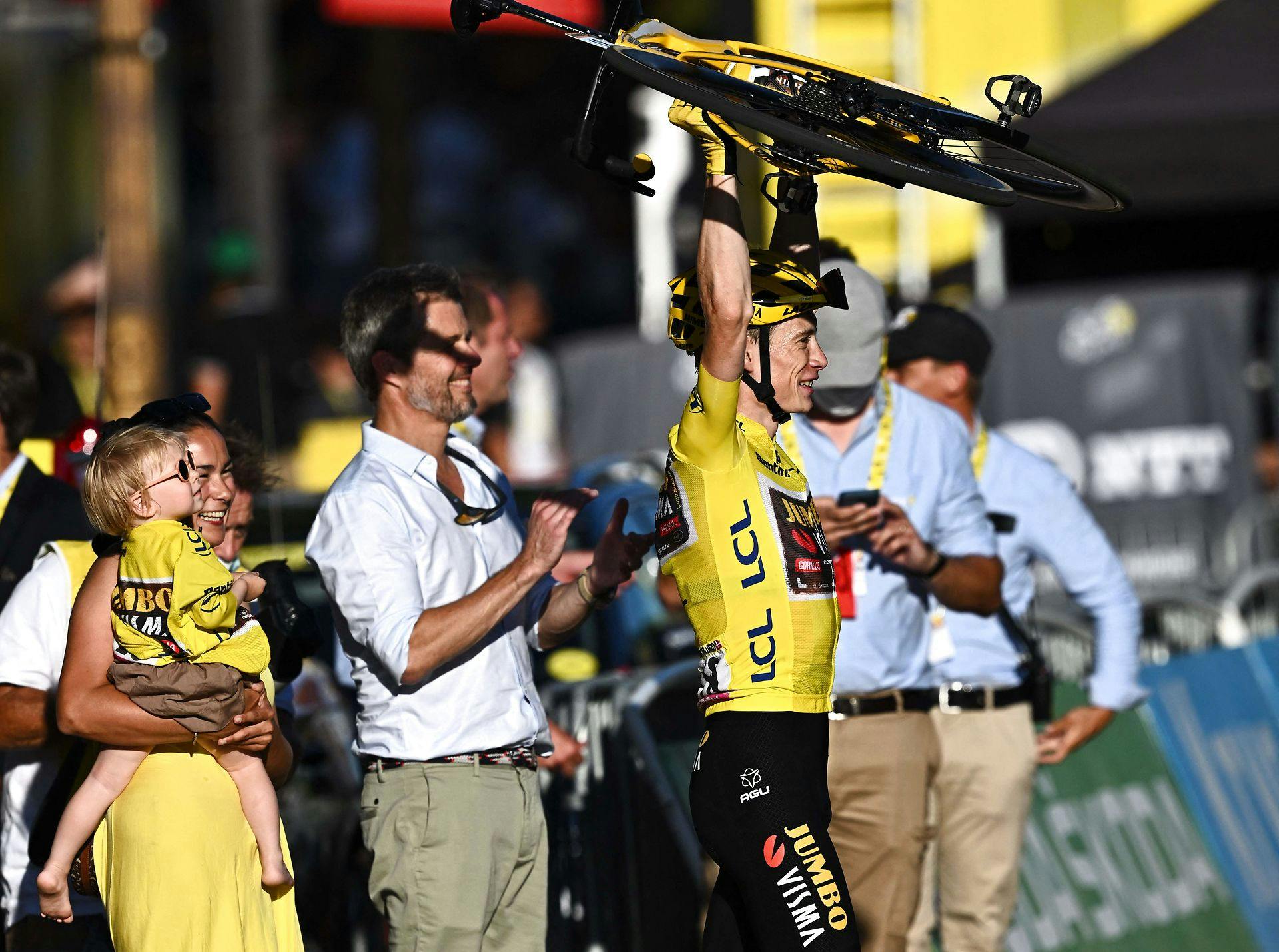 Jonas Vingegaard kunne løfte armene og sin cykel i vejret, da han sejren i Tour de France søndag blev slået endeligt fast. I baggrunden følger Kronprins Frederik og Jonas Vingegaards kæreste og datter med.
