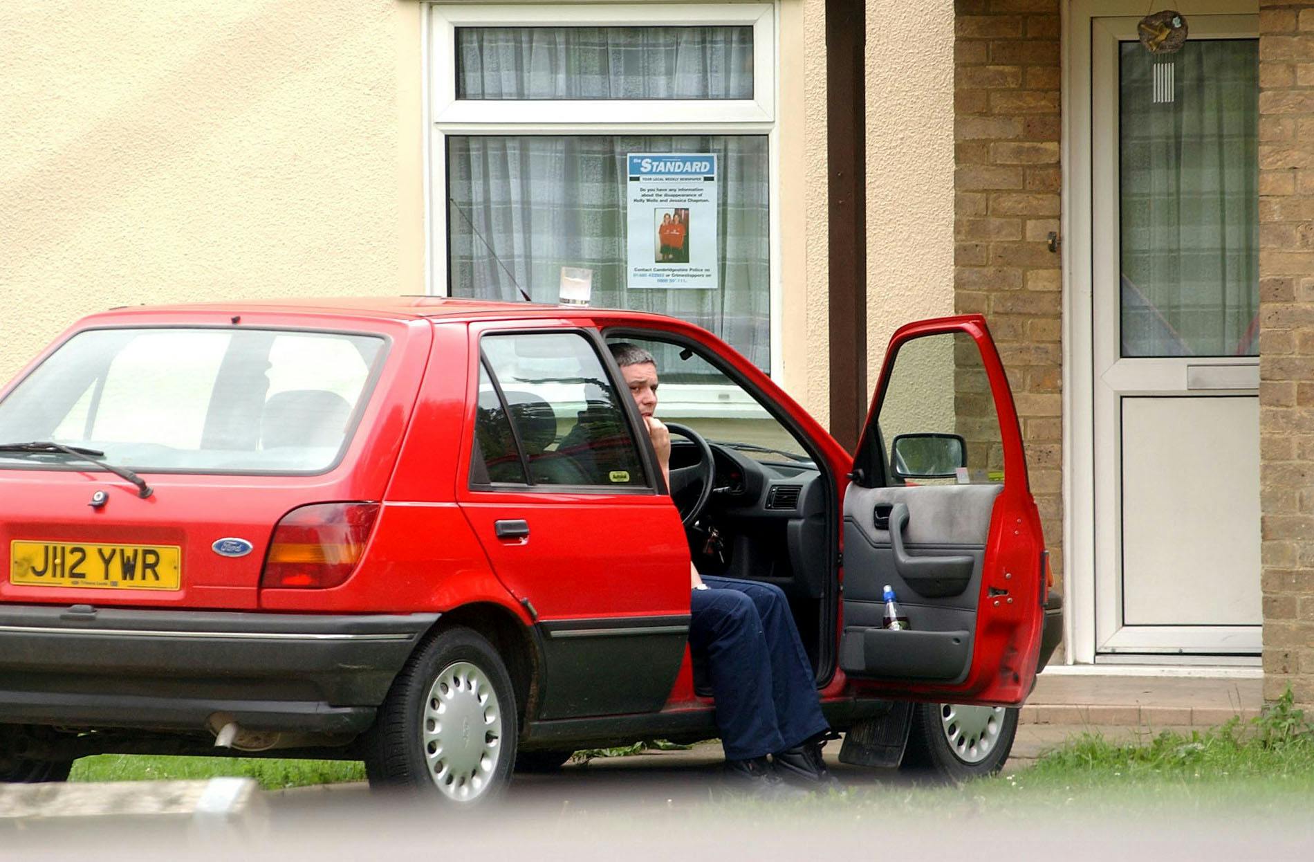 Ian Huntley i sin røde bil få dage inden, han blev anholdt. I hans vindue havde han hængt efterlysningsplakaten af pigerne op.
