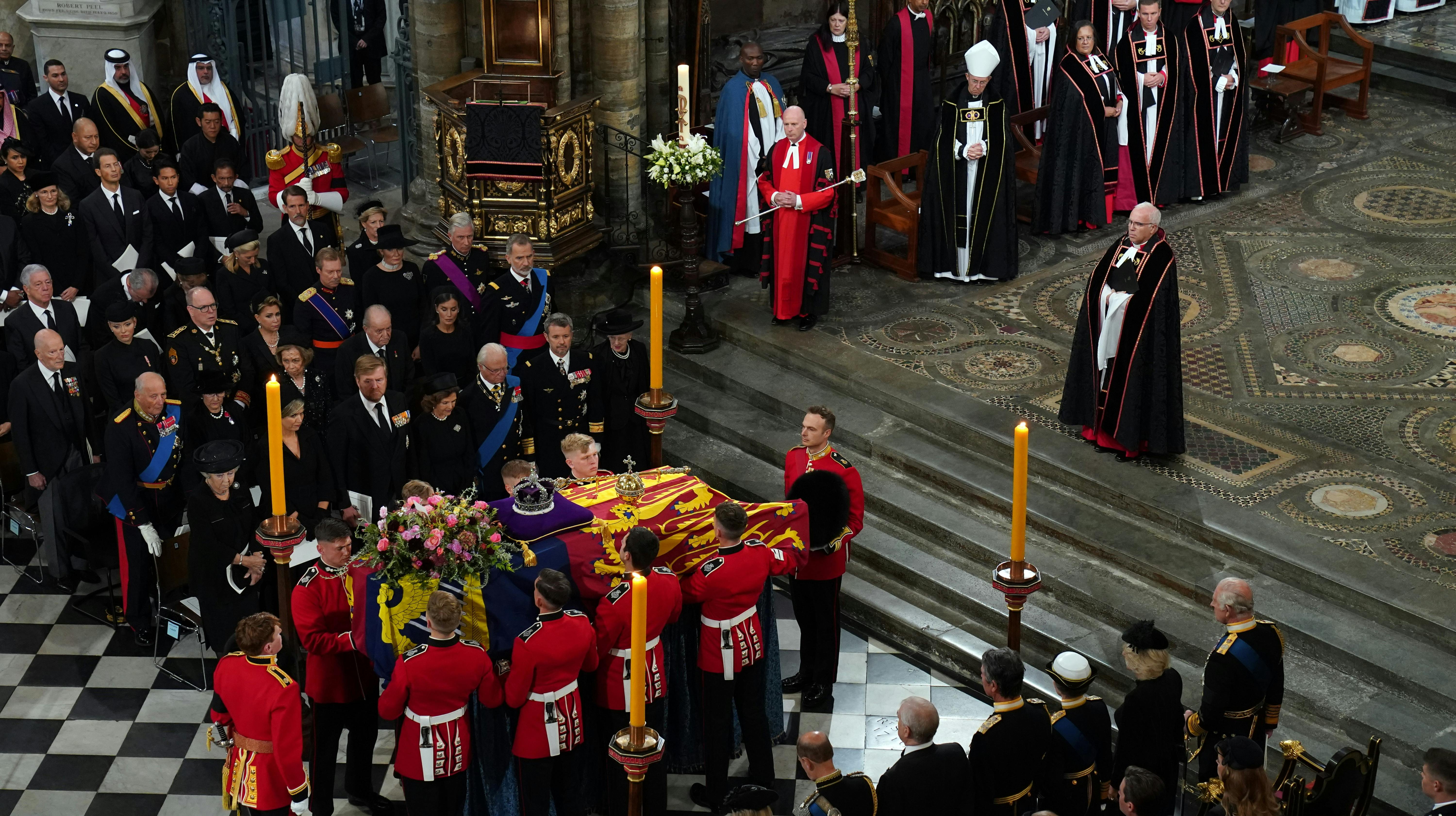 Dronning Margrethe og kronprins Frederik står i midten til venstre for kisten tættest på præsten.