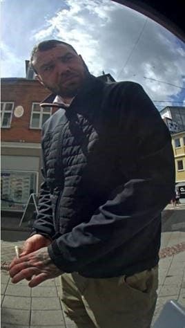 Serie-bedrageren har en synlig tatovering på venstre hånd. Her er han fanget på et overvågningskamera fra en hæveautomat.