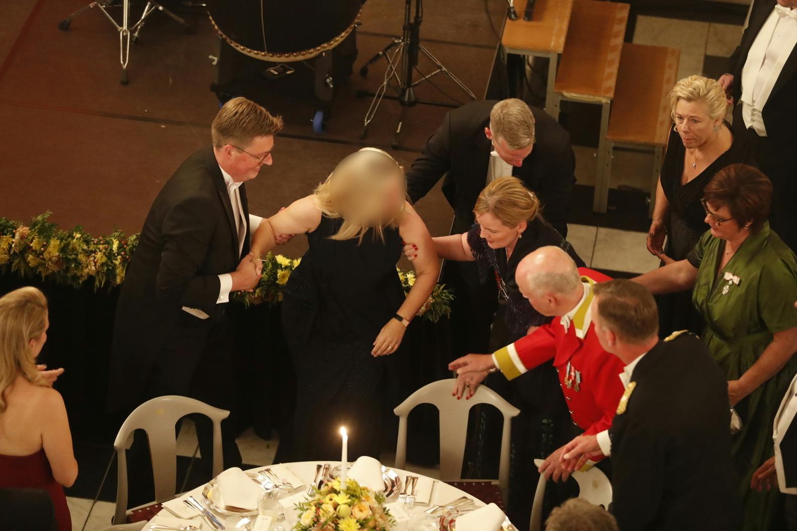 Kvinden hjælpes på benene, efter hun faldt bagover.