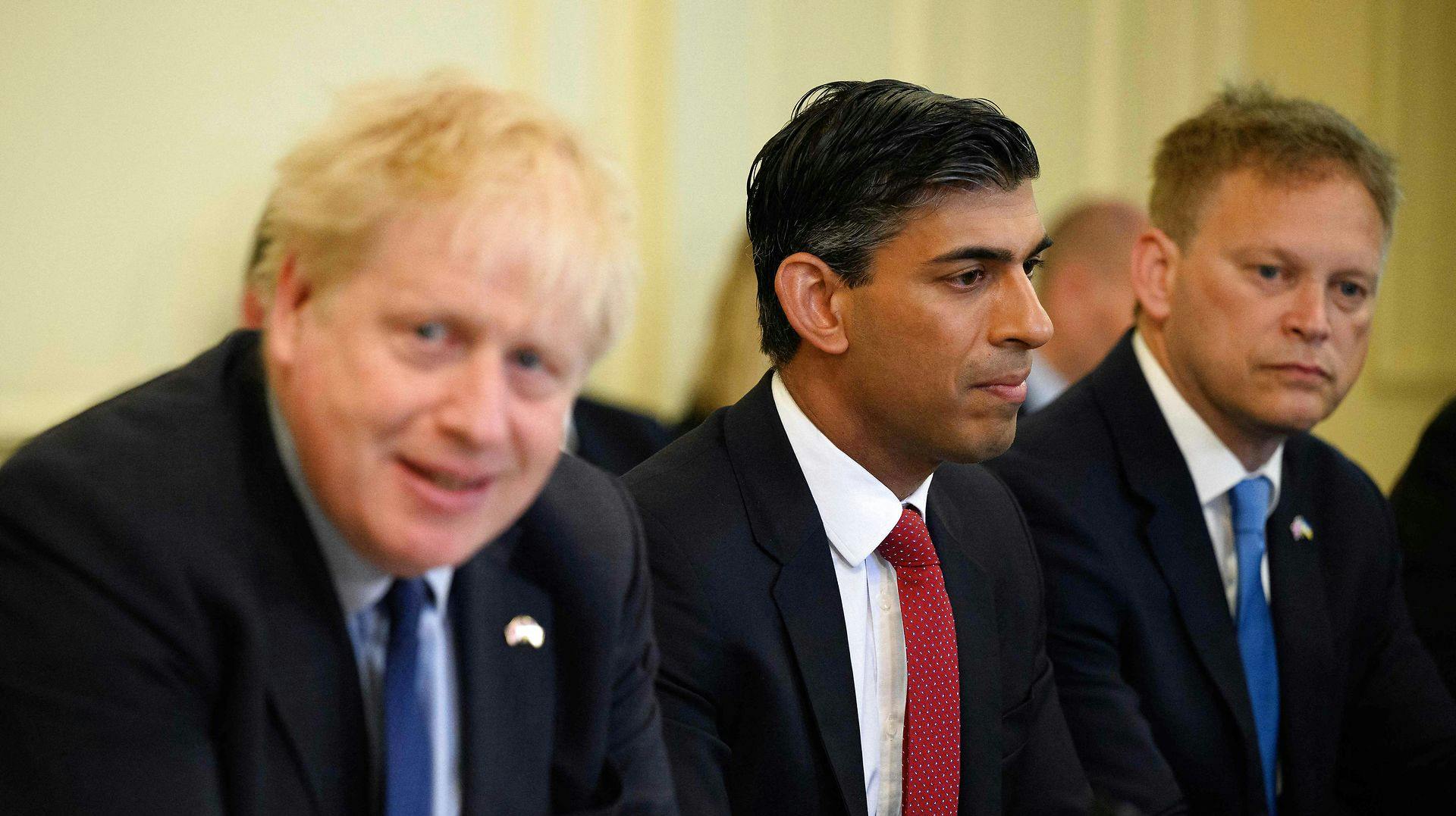 Manden i midten, Rishi Sunak, vil nu sidde for bordenden. Spørgsmålet er, om hans politiske fjende nummer 1, Boris Johnson (t.v.), vil lade ham få jobbet som premierminister.
