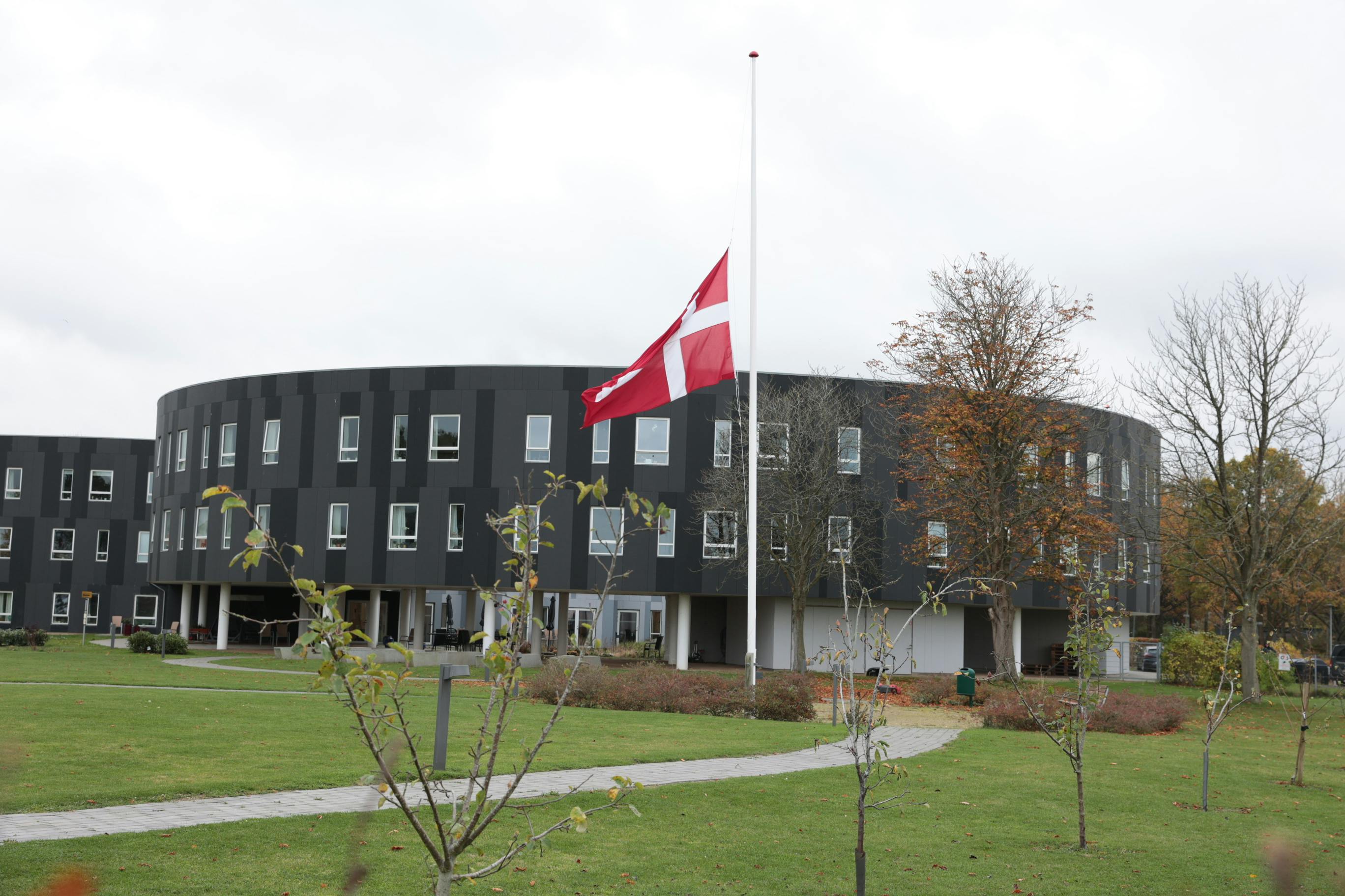 Flaget er på halv foran plejecentret i Holbæk, hvor en ansat&nbsp; - en gravid 37- årig kvinde - torsdag aften blev knivmyrdet.&nbsp;&nbsp;
