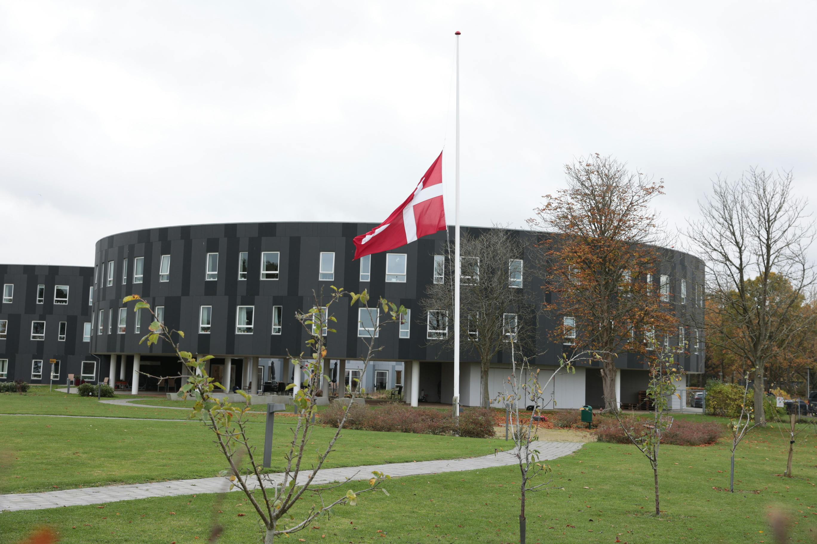 Flaget er på halv foran plejecentret i Holbæk, hvor en ansat - en gravid 37- årig kvinde - torsdag aften blev knivmyrdet. 