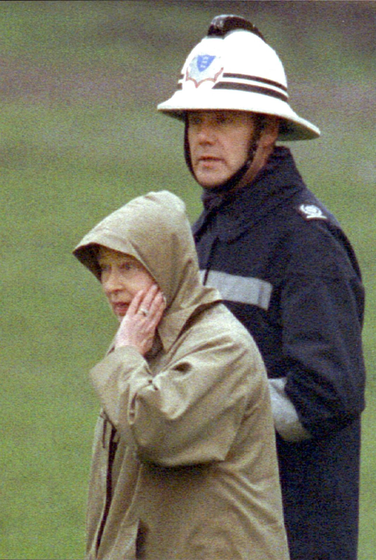 En chokeret dronning Elizabeth bliver vist rundt på Windsor Castle for at bese de omfattende brandskader i 1992.