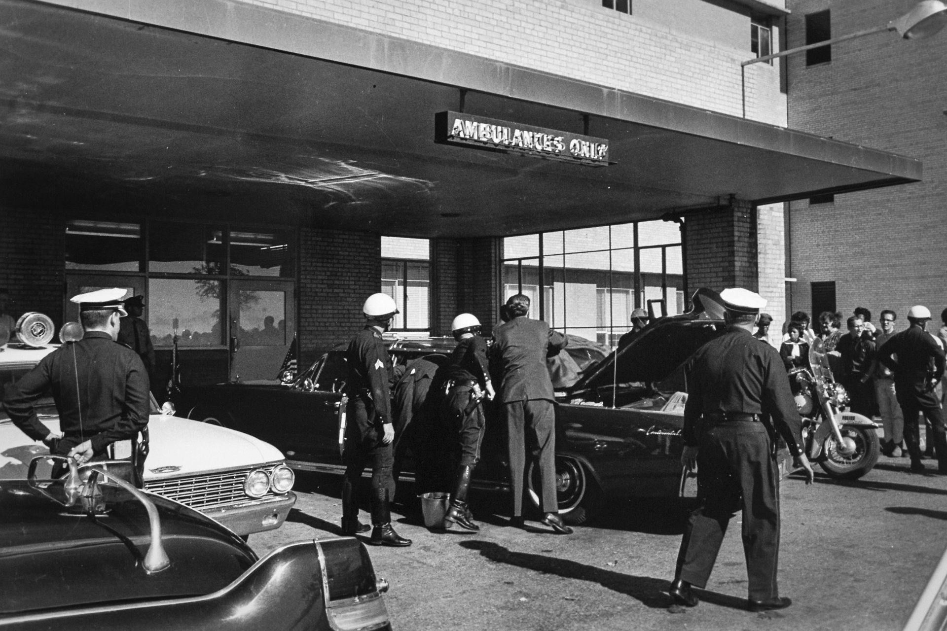 Secret Service-agenter og det lokale politi undersøger præsidentlimousinen, der holder ude foran Parkland Memorial Hospital i Dallas, Texas. Limousinen hastede til hospitalet med den dødeligt sårede præsident.&nbsp;
