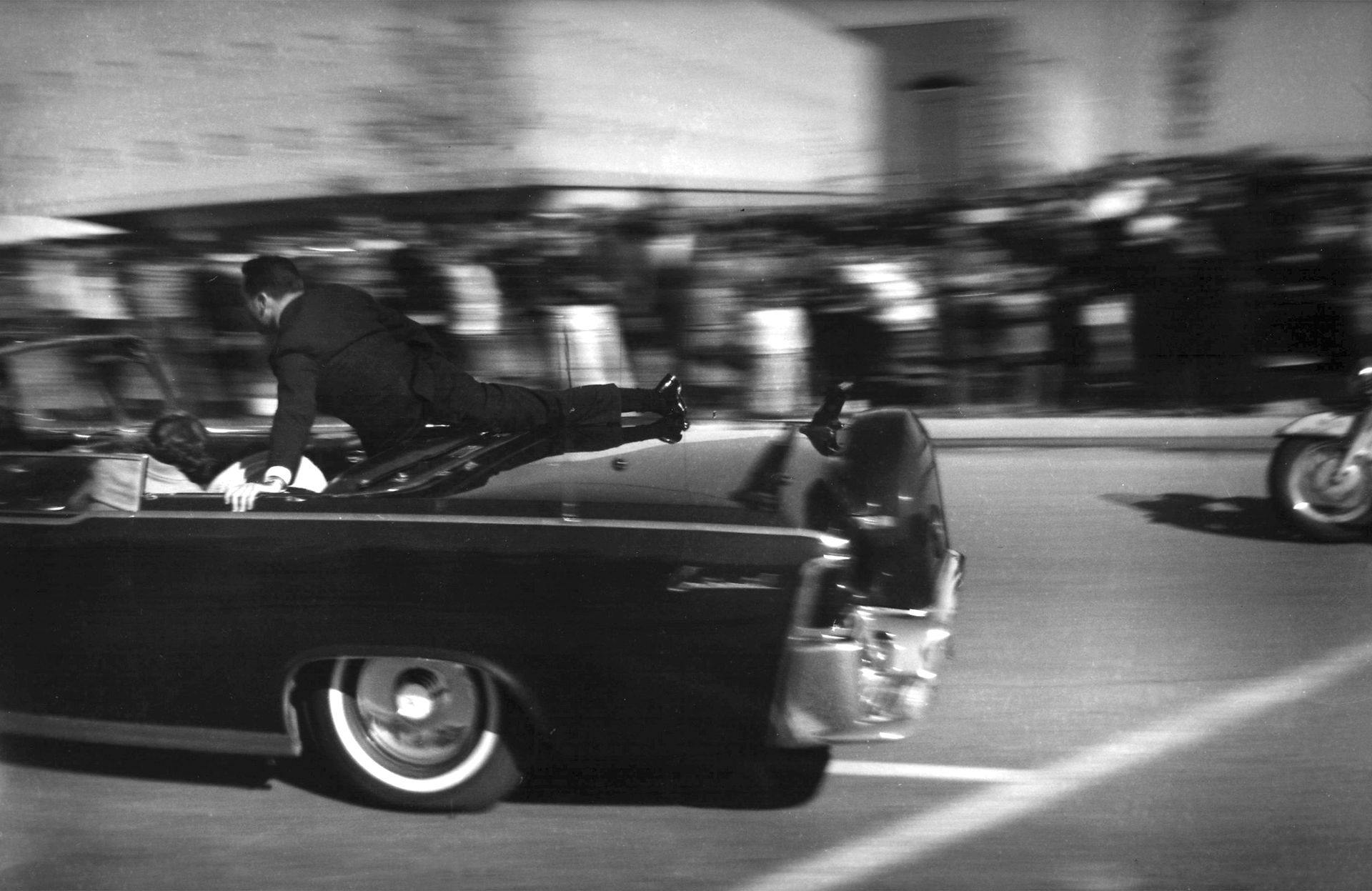 Limousinen med præsidenten ræser mod hospitalet. På bagklappen af bilen sidder Secret Service-agenten Clinton Hill.

&nbsp;
