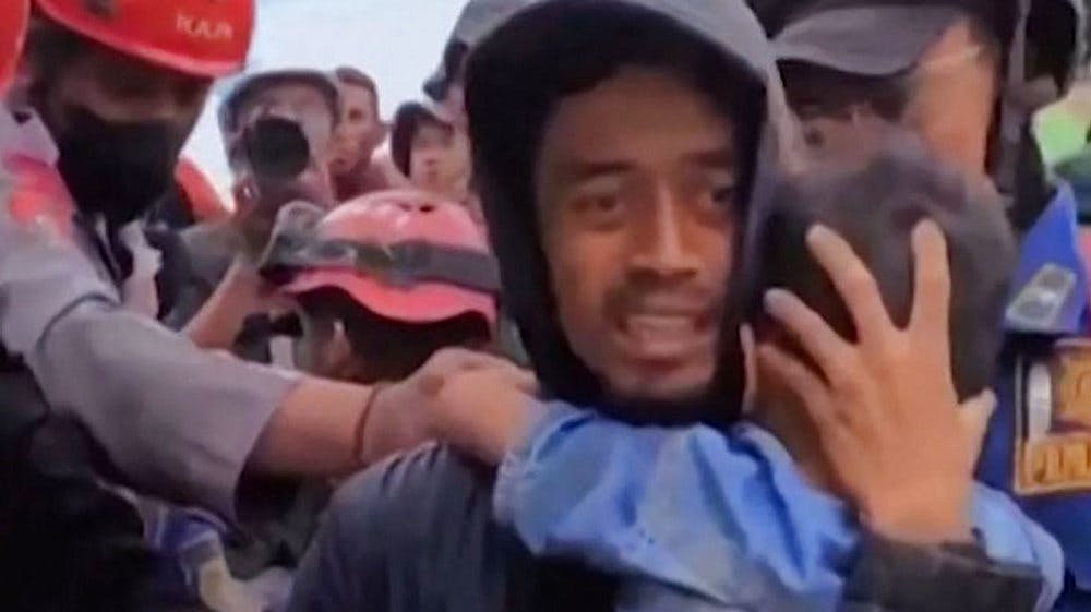 En redningsarbejder holder den seksårige dreng i sine arme. 