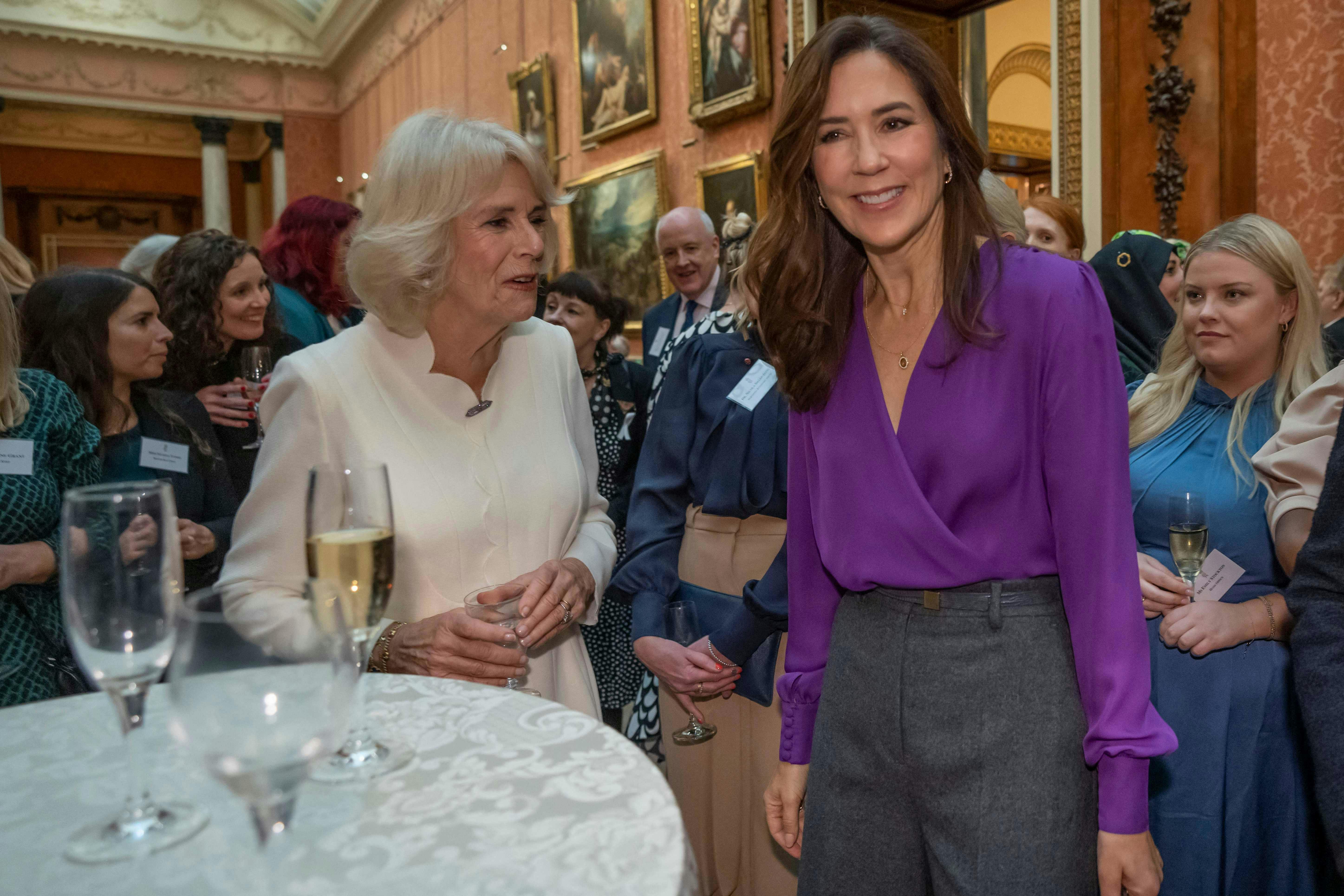 Kronprinsesse Mary får sig her en hyggelig snak med dronning Camilla, der har inviteret til reception på Buckingham Palace.&nbsp;