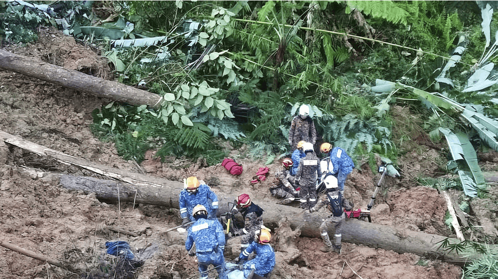 Personale fra Malaysias civilforsvar arbejder på at redde mennesker, der er fanget efter et jordskred. 