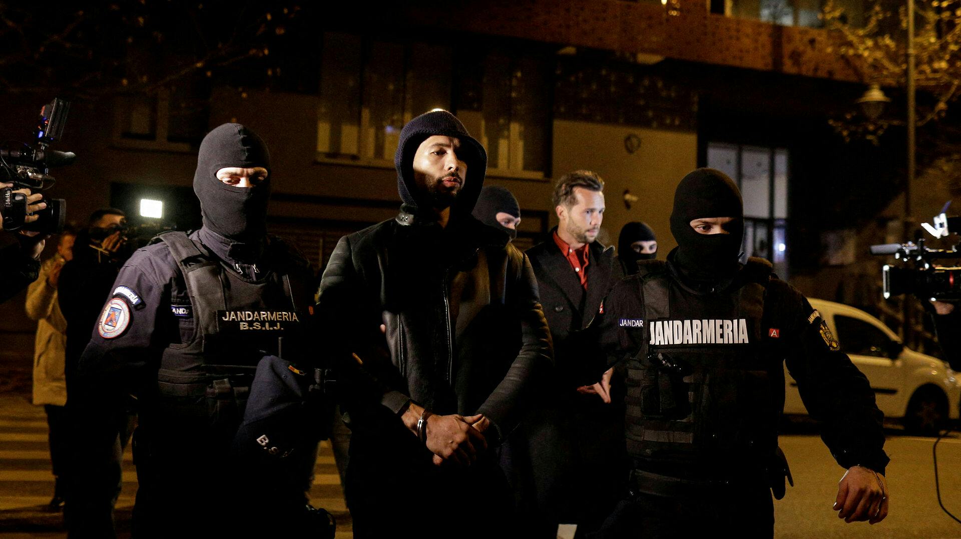 Her bliver Andrew Tate og Tristan Tate eskorteret væk af politiet. 