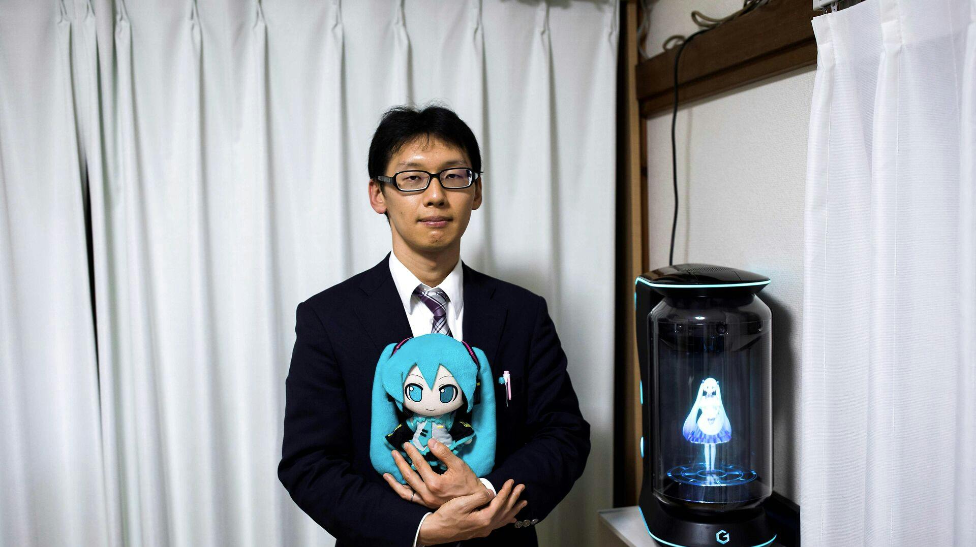 Akihiko Kondo på 38 år har både dukker og figurer af sin kæreste. Indtil for nylig kunne de kommunikere via en hologrammaskine, men firmaet bag maskinen har valgt at slukke for supporten til softwaren. 