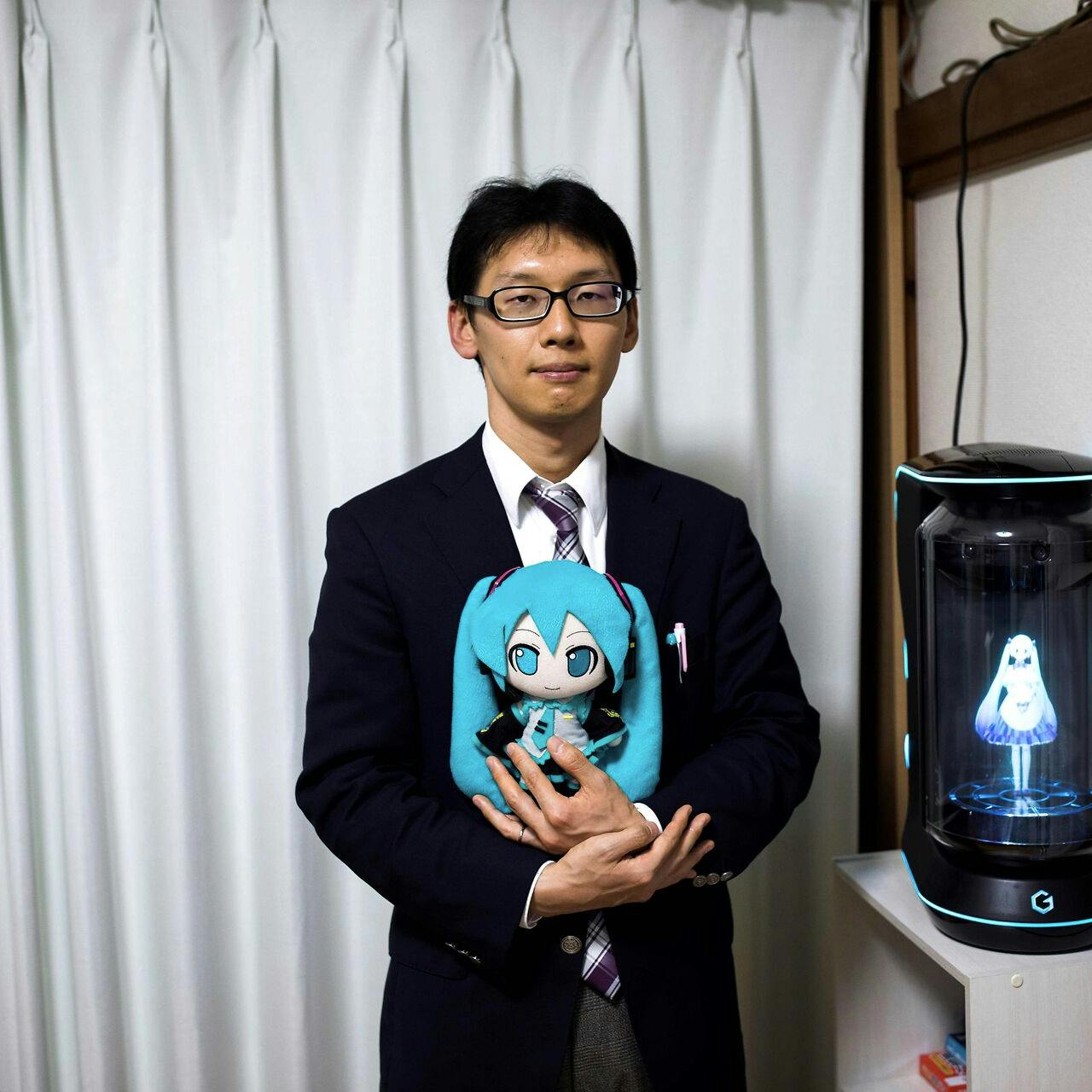 Akihiko Kondo på 38 år har både dukker og figurer af sin kæreste. Indtil for nylig kunne de kommunikere via en hologrammaskine, men firmaet bag maskinen har valgt at slukke for supporten til softwaren. 