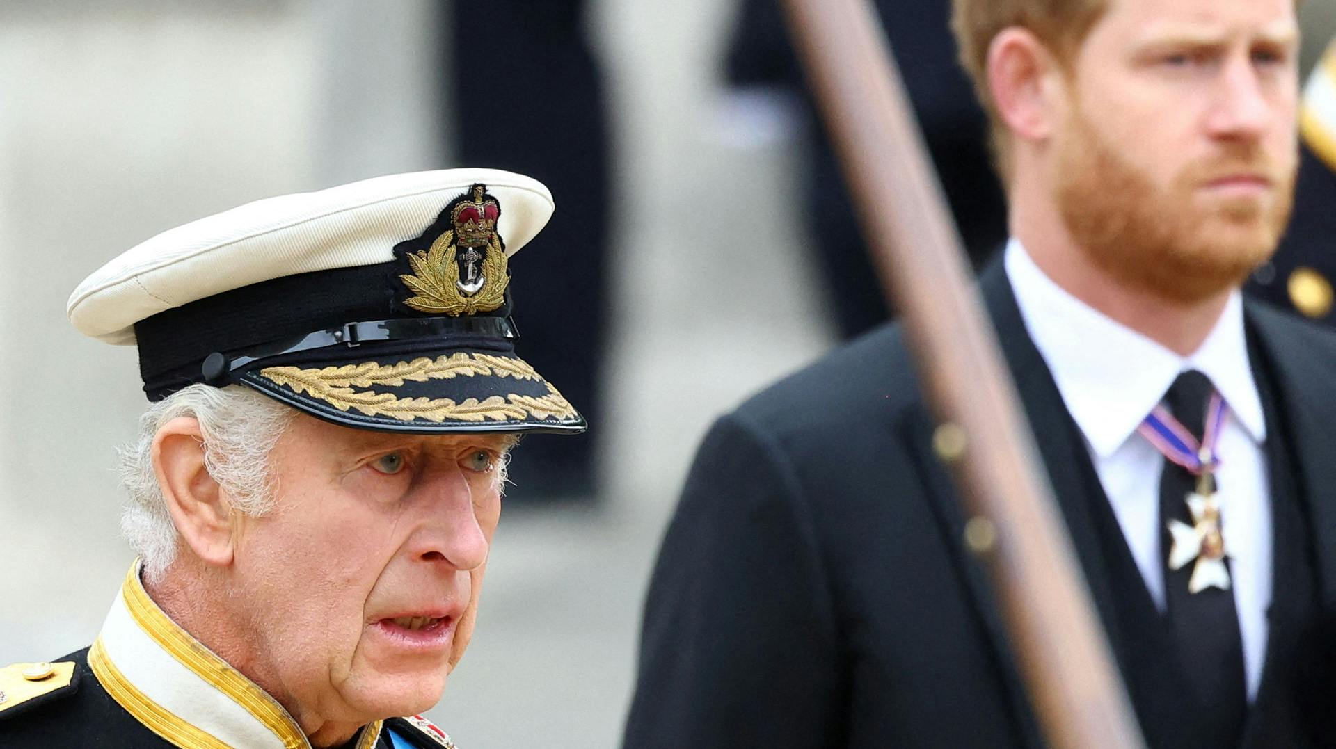 Kong Charles med prins Harry i baggrunden.