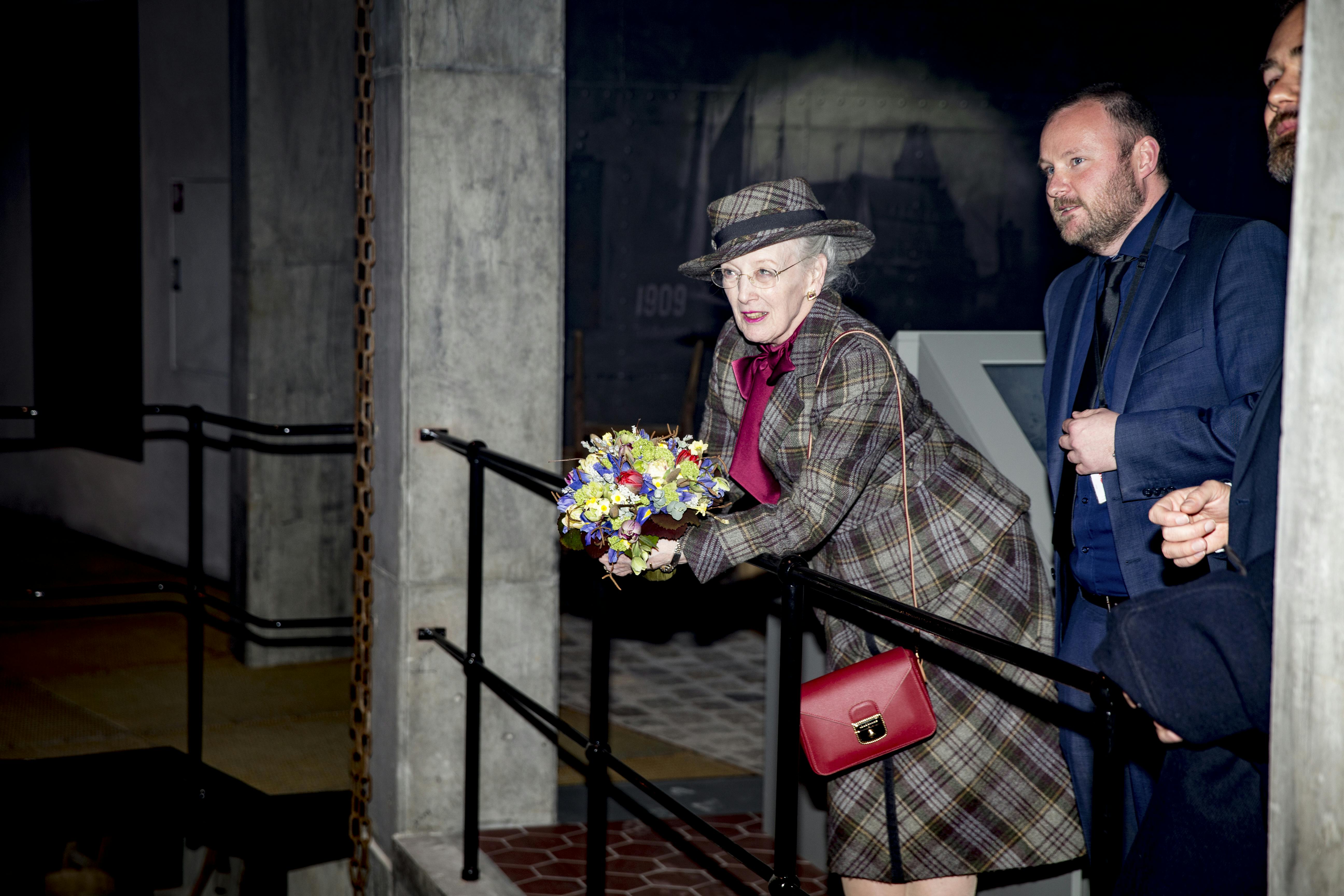 Dronningen plejer at have manererne i orden, men smerterne blev for stærke, da hun i 2017 åbnede en ny udstilling i Den gamle by i Aarhus. Majestæten tog sig et lille hvil ind over gelænderet.