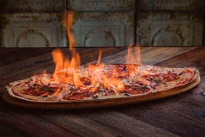 Et billede fra restaurantens egen hjemmesiden af en pizza med ild i. 