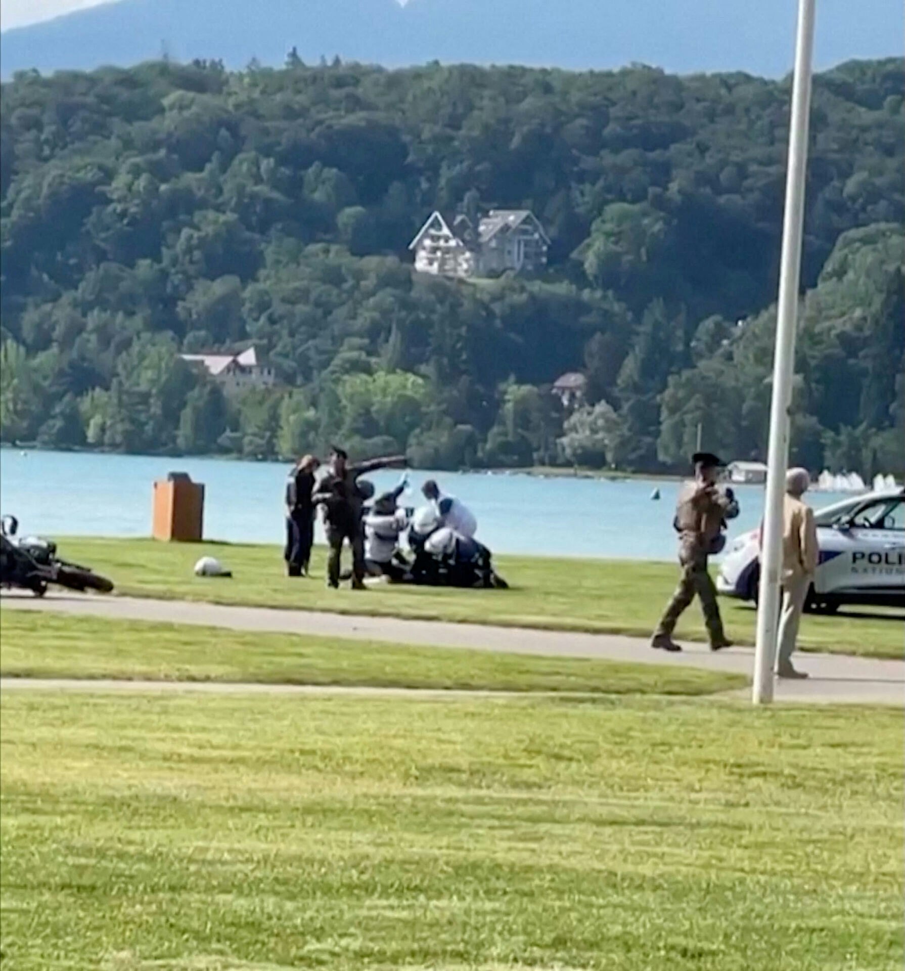Et billede af fransk politi i gang med at arrestere den formodede gerningsmand efter et knivstikkeri i en park i Annecy, Frankrig torsdag morgen.