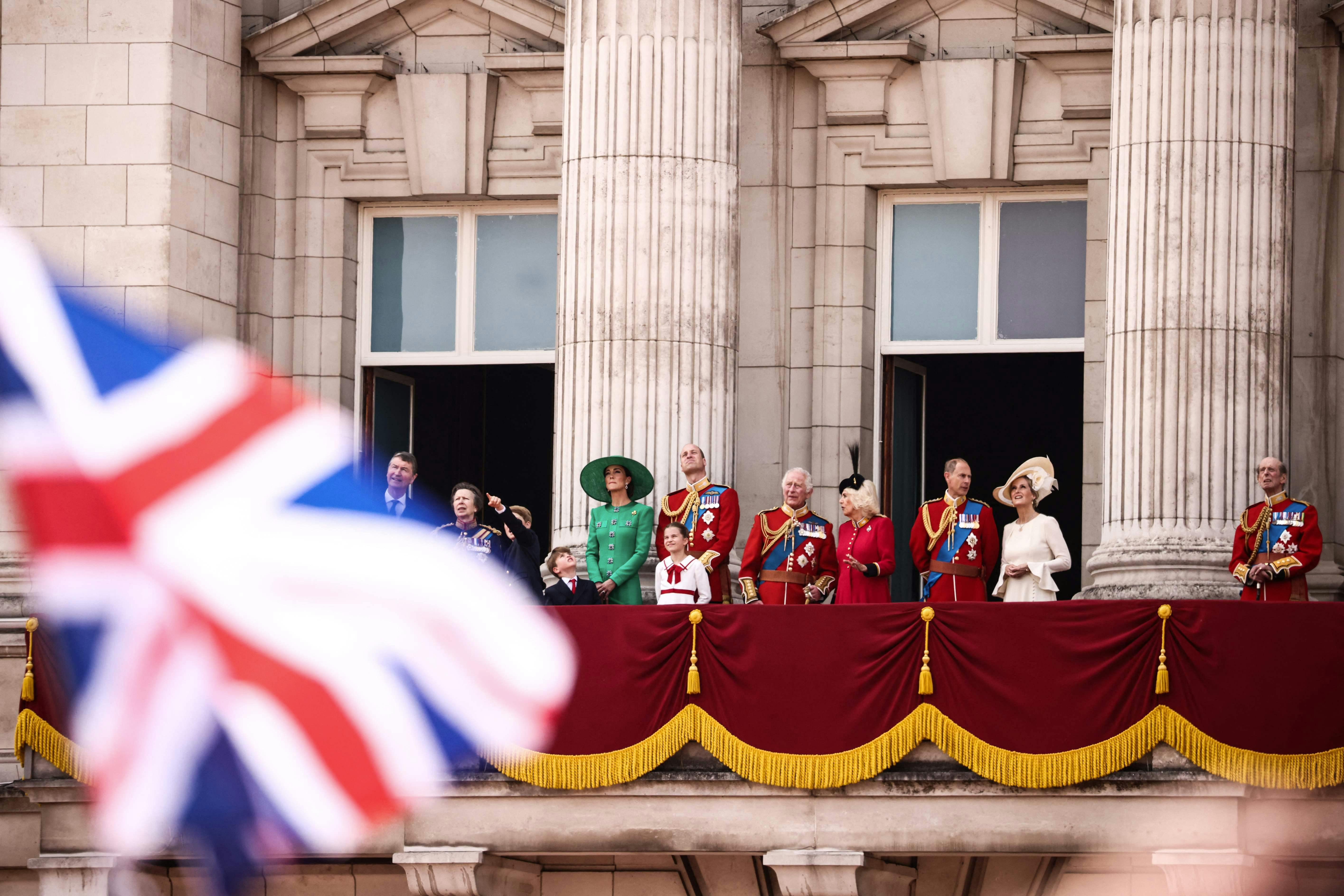 Fra venstre mod højre er det Timothy Laurence, der står med sin hustru prinsesse Anne, dernæst er det prins George, prins Louis, prinsesse Kate, prins William, prinsesse Charlotte, kong Charles, dronning Camilla, prins Edwards og hertuginde Sophie, der