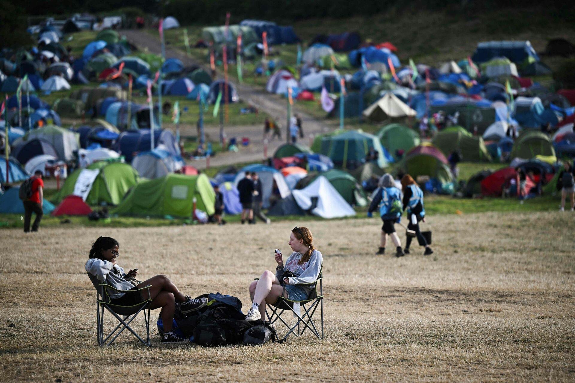 Festival goers sit on camping chairs at the end of Glastonbury festival in the village of Pilton in Somerset, southwest England, on June 26, 2023. The festival takes place from June 21 to June 26. (Photo by Oli SCARFF / AFP)