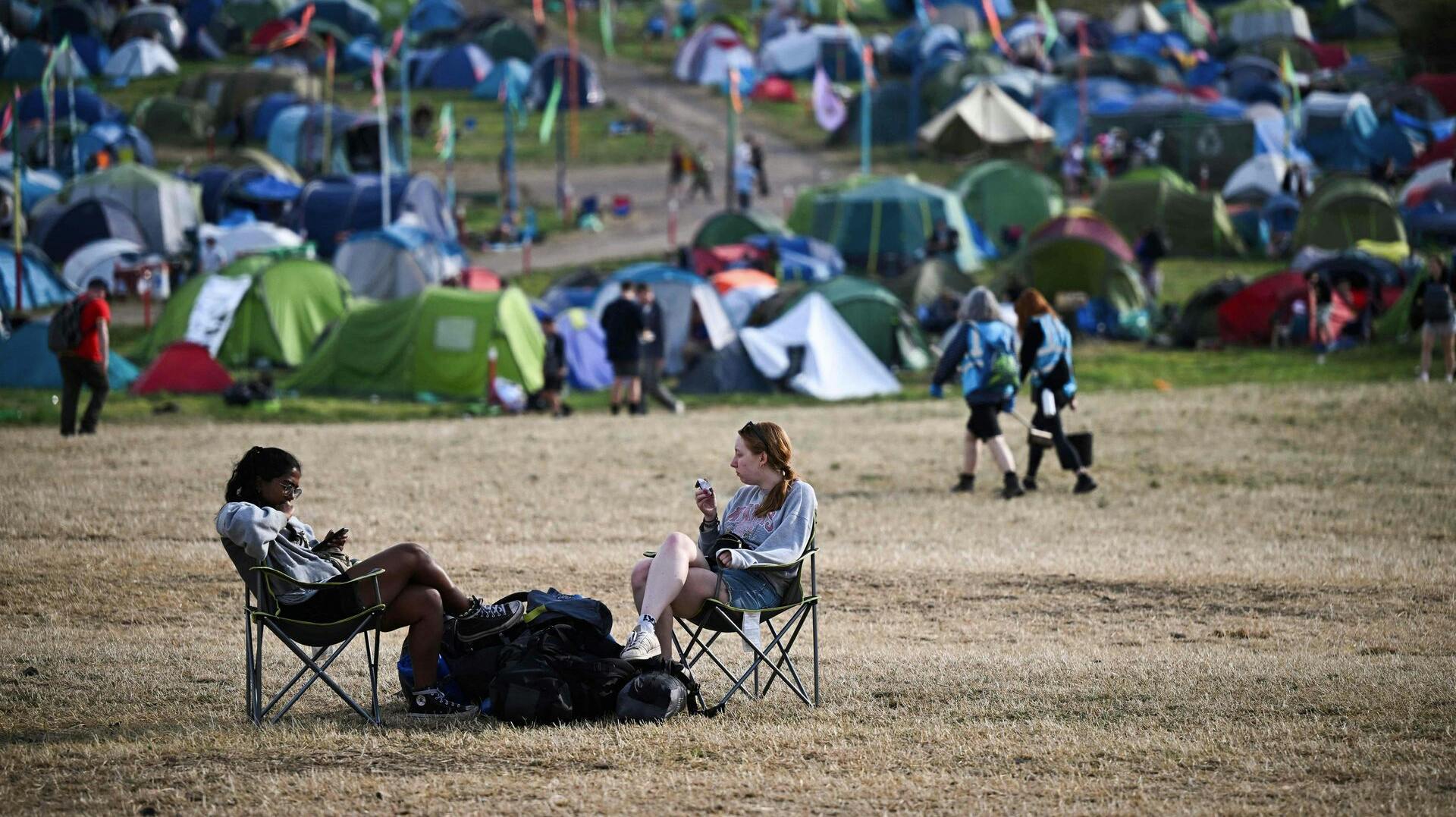 Festival goers sit on camping chairs at the end of Glastonbury festival in the village of Pilton in Somerset, southwest England, on June 26, 2023. The festival takes place from June 21 to June 26. (Photo by Oli SCARFF / AFP)