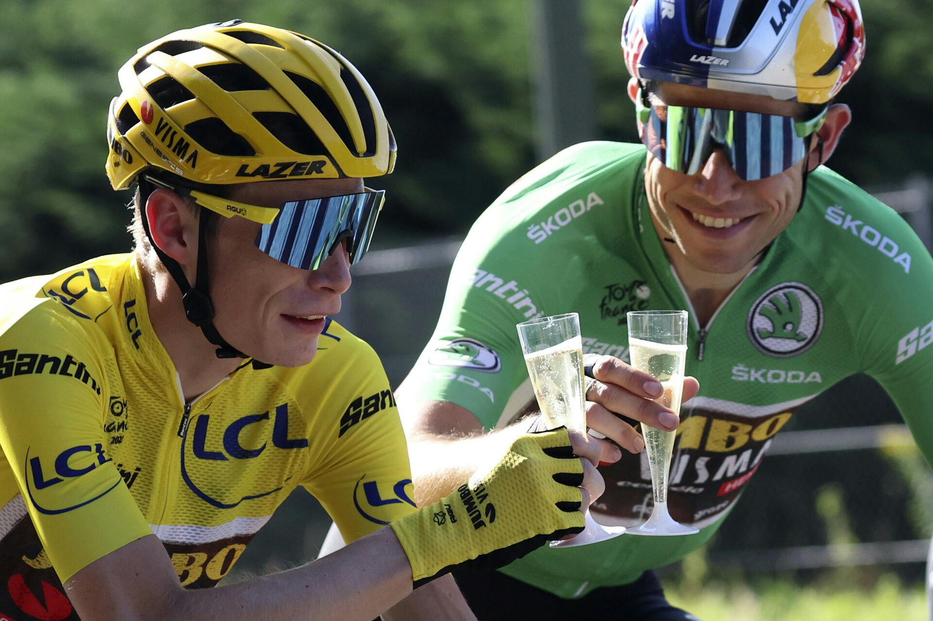 Denmark's Jonas Vingegaard, wearing the overall leader's yellow jersey, toasts champagne with teammates Belgium's Wout Van Aert, wearing the best sprinter's green jersey during the twenty-first stage of the Tour de France cycling race over 116 kilometers (72 miles) with start in Paris la Defense Arena and finish on the Champs Elysees in Paris, France, Sunday, July 24, 2022. (Thomas Samson/Pool Photo via AP)