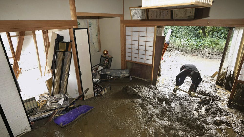 En mand forsøger at fjerne mudderet fra sit hjem i den sydvestlige del af Japan, hvor store mængder nedbør har forårsaget oversvømmelser og jordskred.