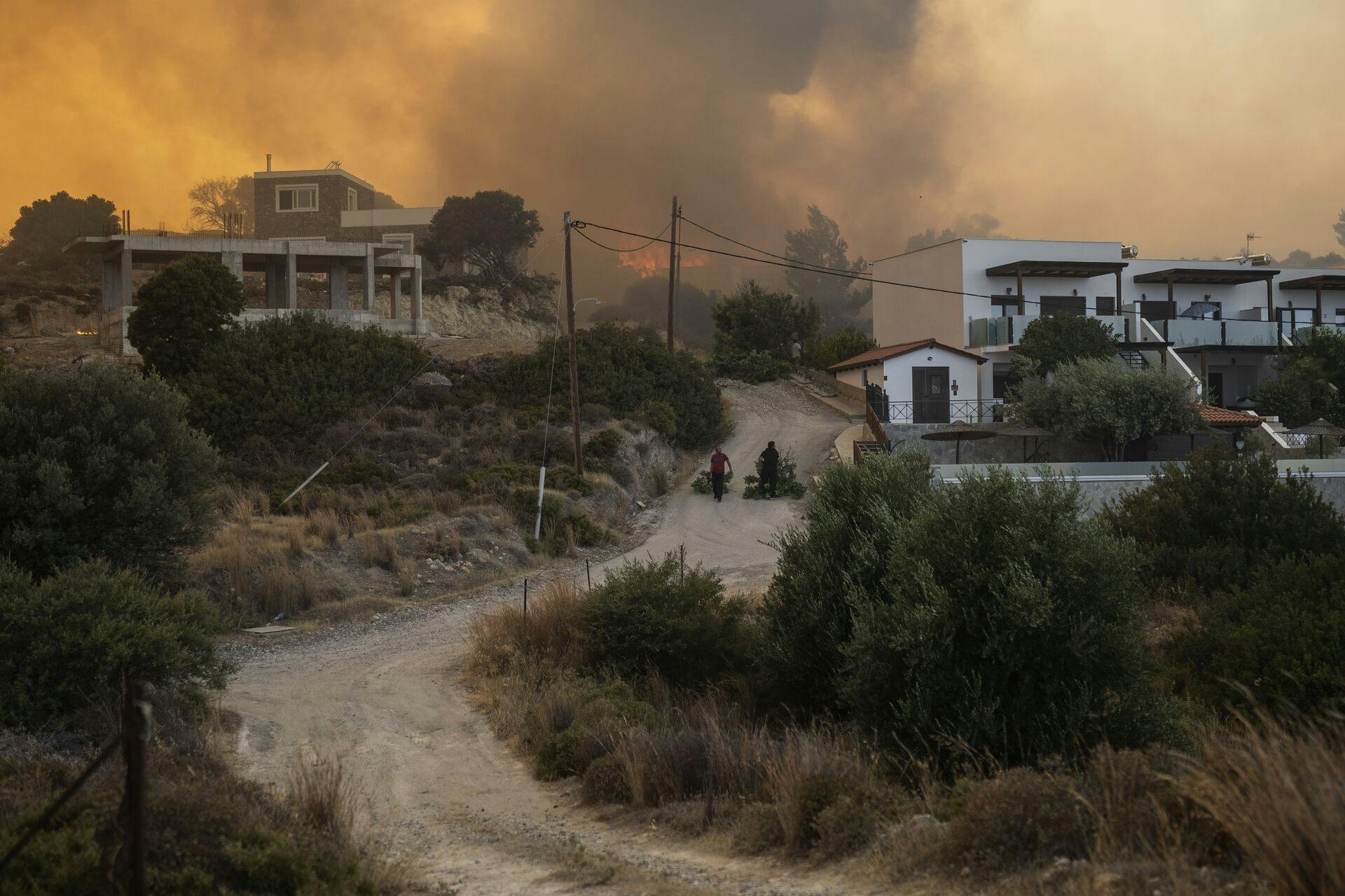 Locals pull tree branches as a wildfire burns in Gennadi village, on the Aegean Sea Island of Rhodes, southeastern Greece, on July 25, 2023. (AP Photo/Petros Giannakouris)