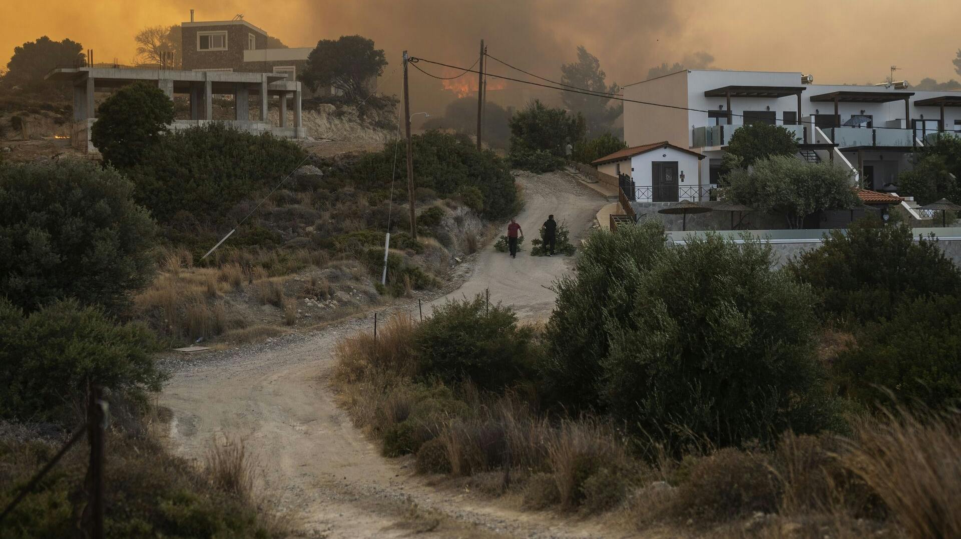 Locals pull tree branches as a wildfire burns in Gennadi village, on the Aegean Sea Island of Rhodes, southeastern Greece, on July 25, 2023. (AP Photo/Petros Giannakouris)