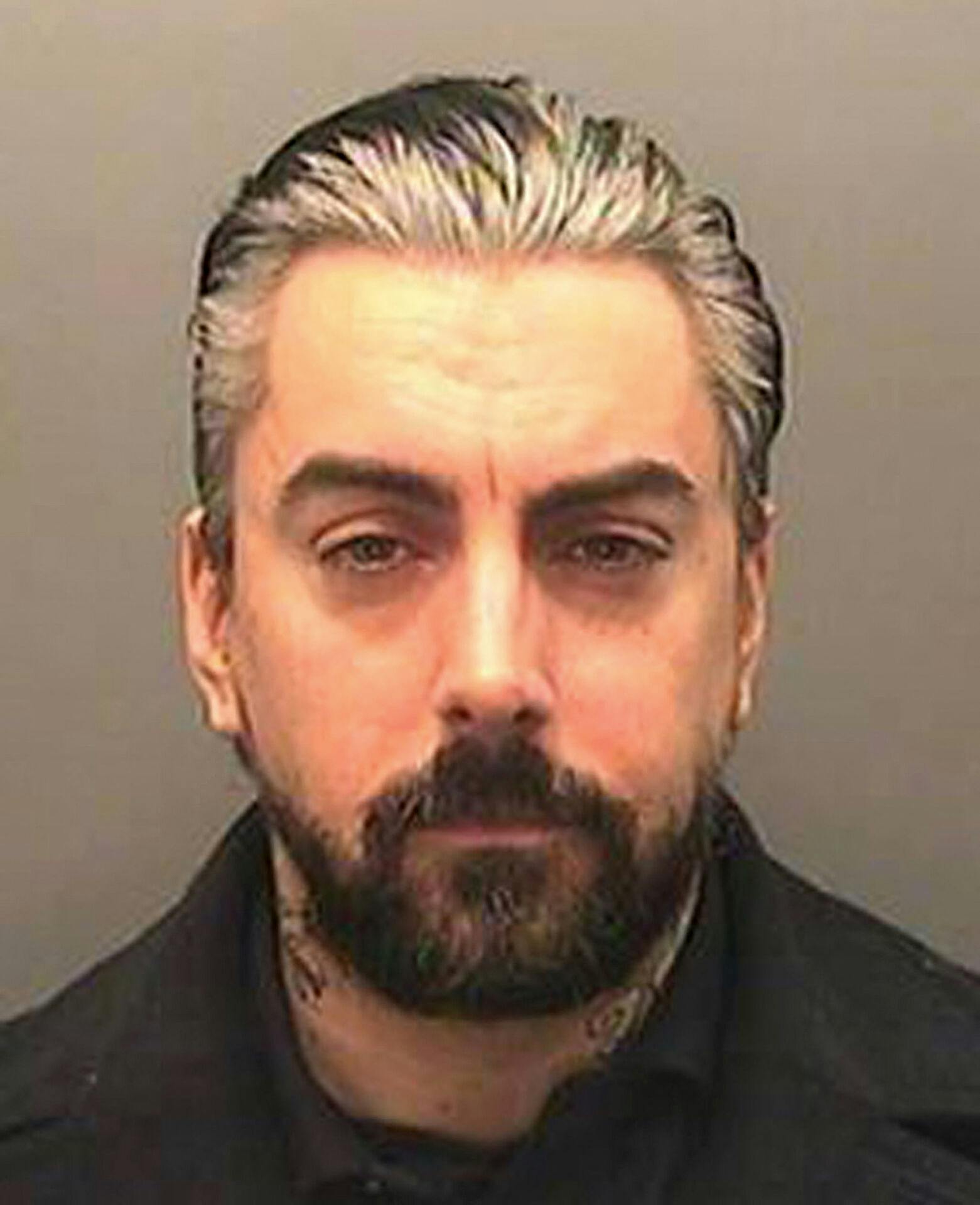 Ian Watkins såkaldte mugshot fra 2013, hvor han blev anholdt og sigtet for alvorlige seksualforbrydelser begået mod helt små børn - hvilket han siden blev idømt 35 års fængsel for.