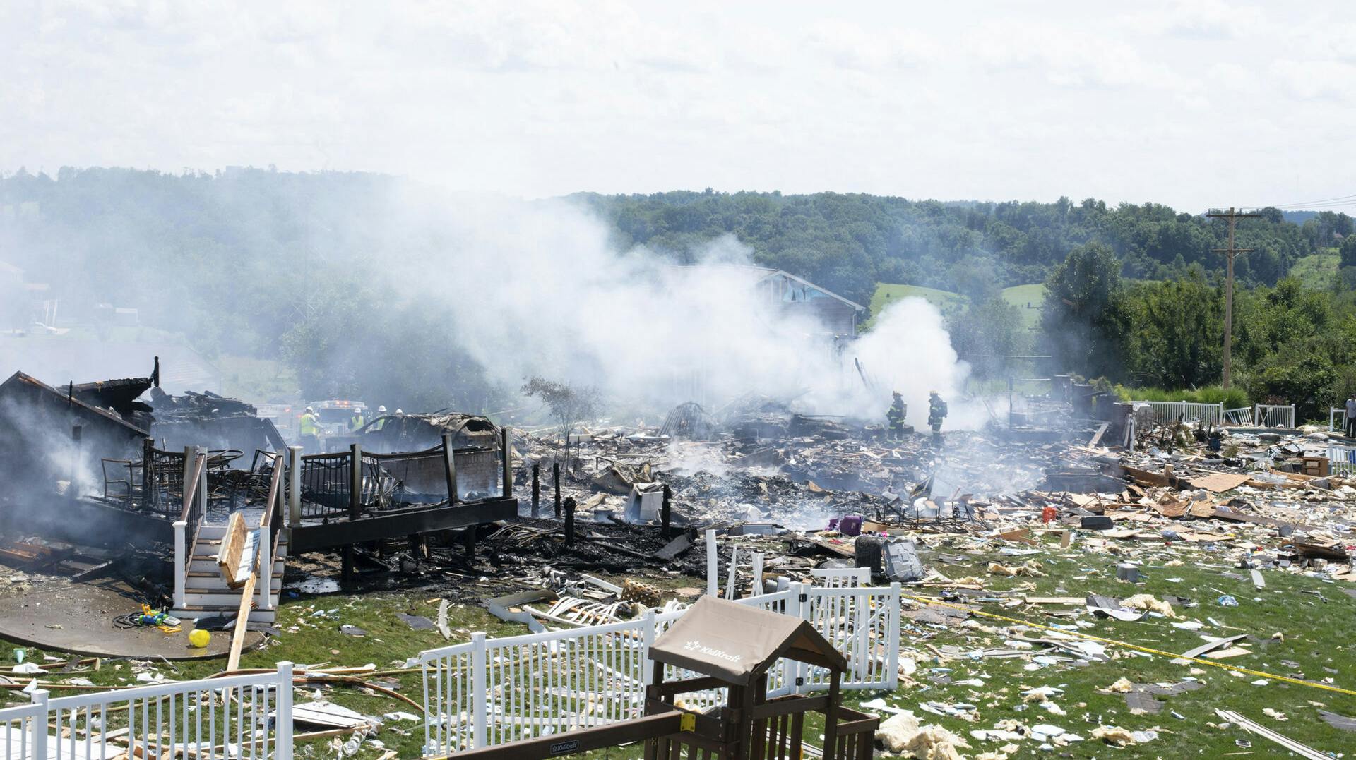 Two firefighters stand on the debris around the smoldering wreckage of the the three houses that exploded near Rustic Ridge Drive and Brookside Drive in Plum, Pa., on Saturday, Aug. 12, 2023. (Samuel Long/Pittsburgh Post-Gazette via AP)