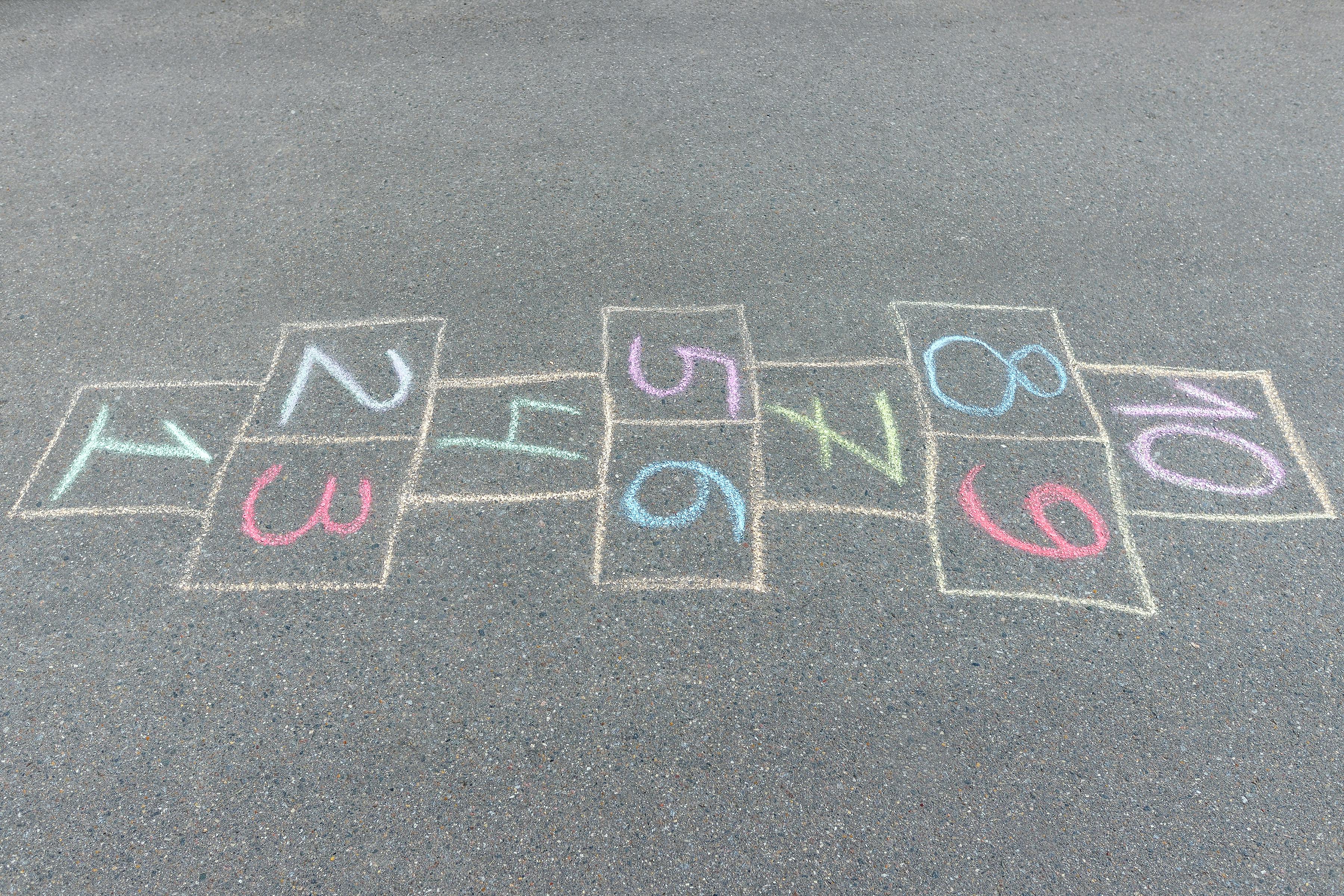 Close-up photo of chalk painted hopscotch on asphalt. School yard. Back to school. Outdoor activities for kids.