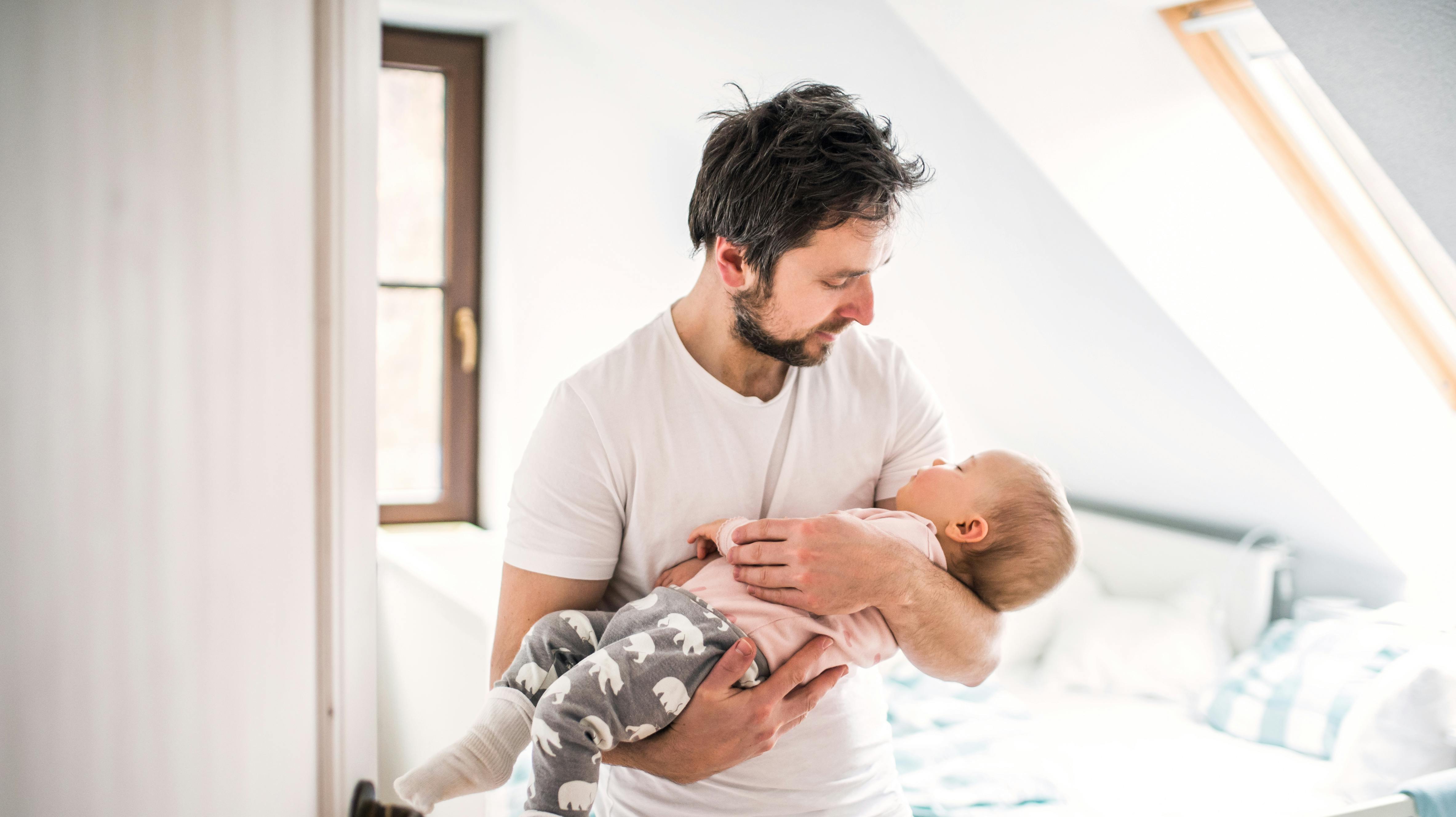 Mature father carrying a sleeping toddler girl in bedroom at home. Paternity leave.
