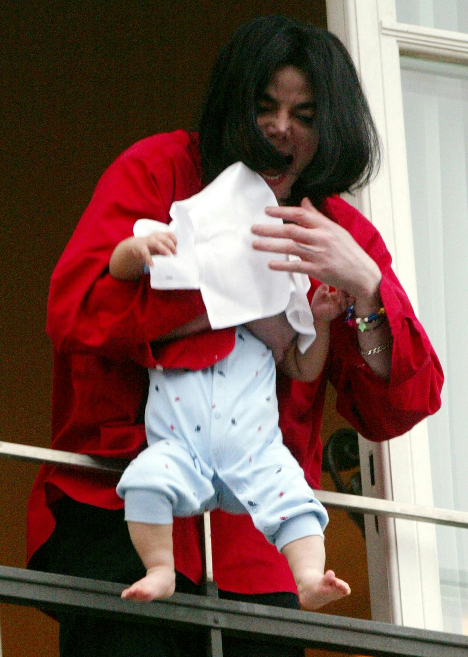 Singer Michael Jackson is pictured holding a child out of a window as he looks at fans after arriving at a Berlin hotel, in this November 19, 2002 file photo. Pop giant Michael Jackson, who took to the stage as a child star and set the world dancing to exuberant rhythms for decades, died on June 25, 2009, after being taken ill at his home, the Los Angeles Times said. He was 50. REUTERS/Tobias Schwarz/Files (GERMANY)