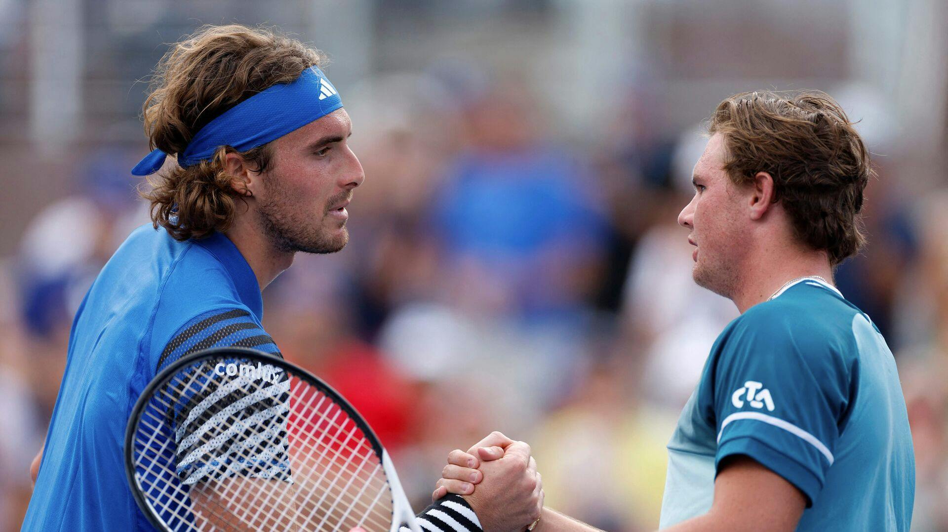 Tsitsipas (tv) lykønsker sin 21-årige modstander ved nettet. Det var der nok ikke nogen af de to, som havde forestillet sig små fem sæt og fire timer inden.