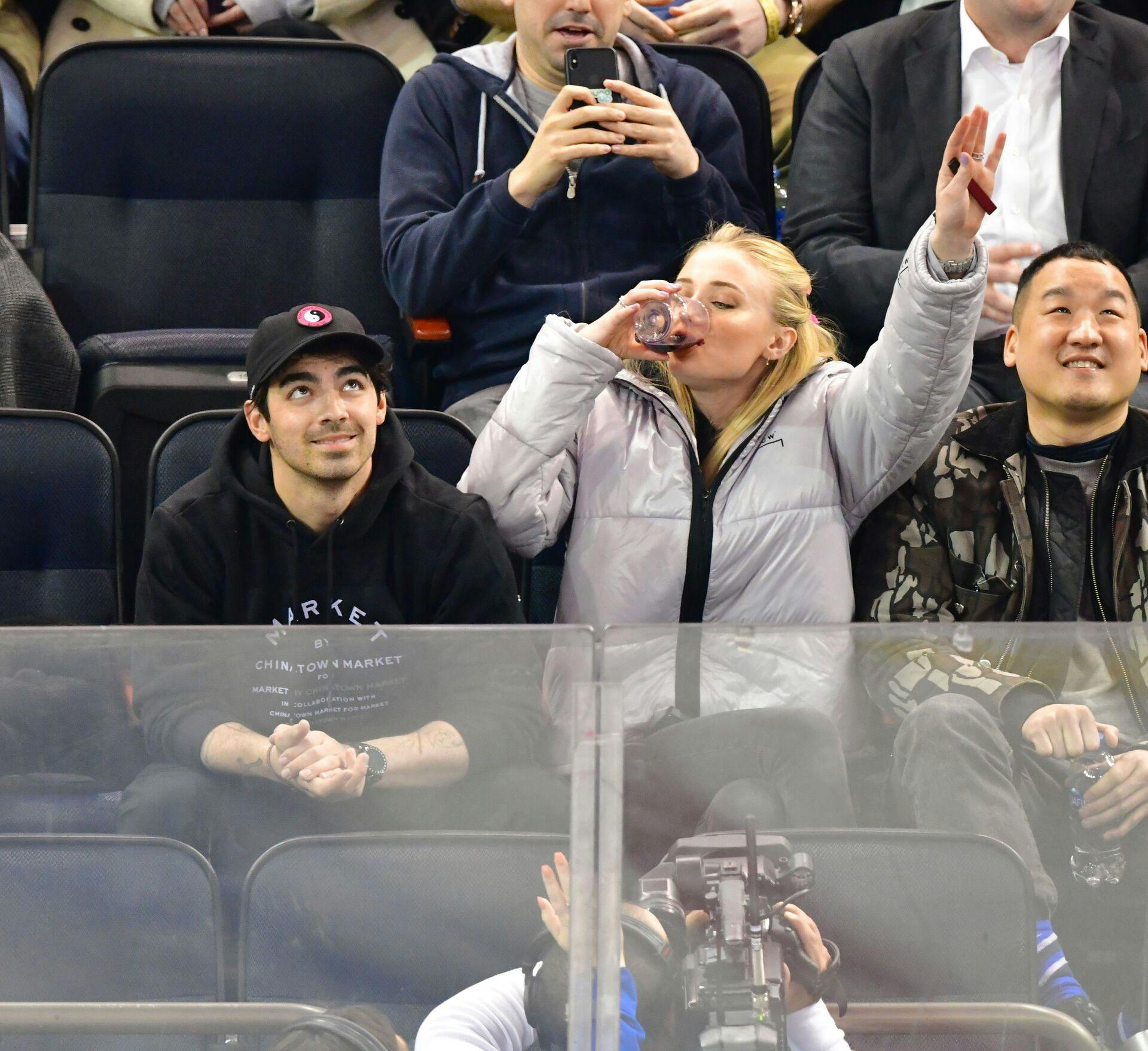 Sophie Turner bæller rødvin til en ishockeykamp i Madison Square Garden i New York i 2019.