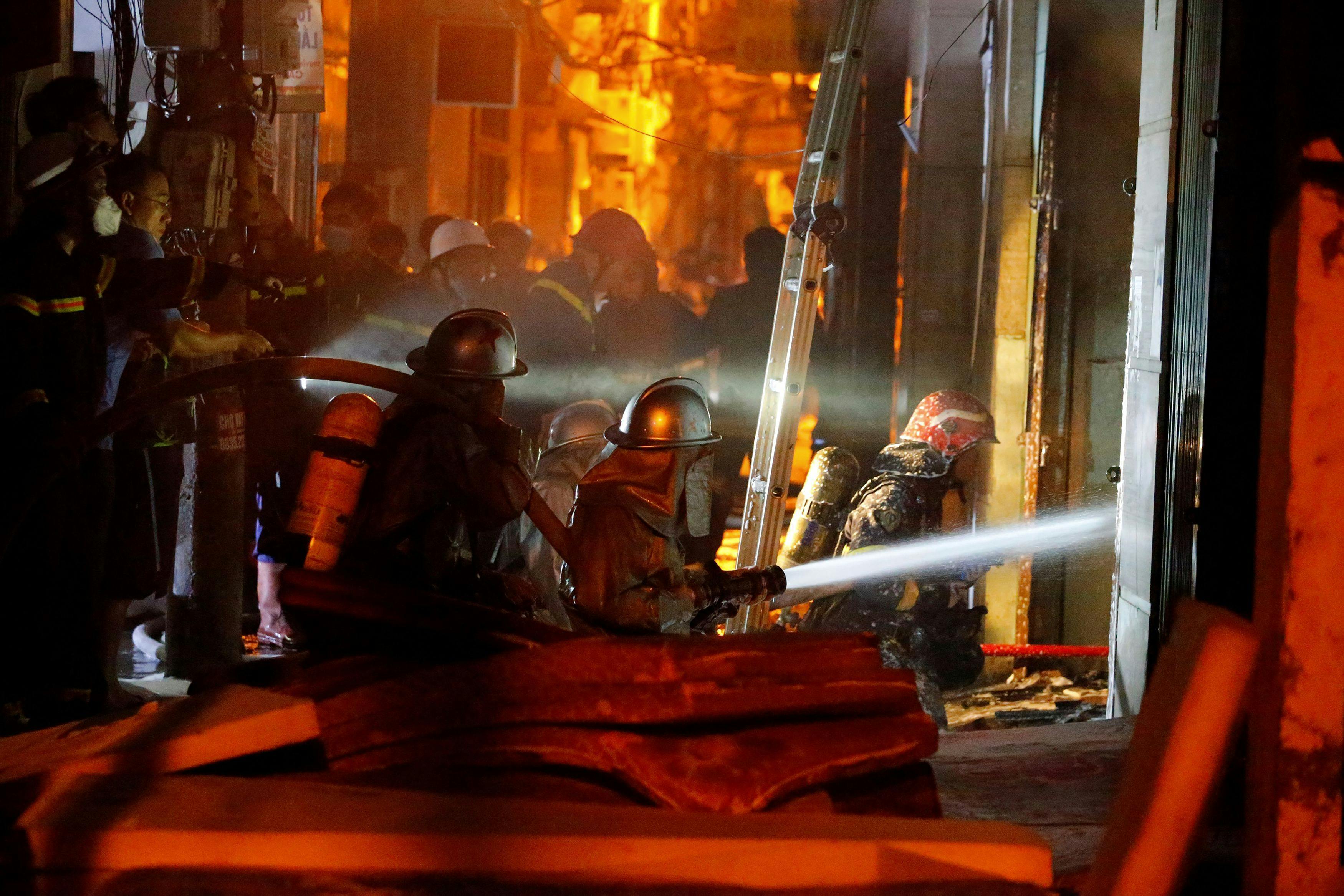 TOPSHOT - Firefighters work to put out a fire and rescue people at an apartment block in Hanoi on September 13, 2023. (Photo by LE PHU / AFP)