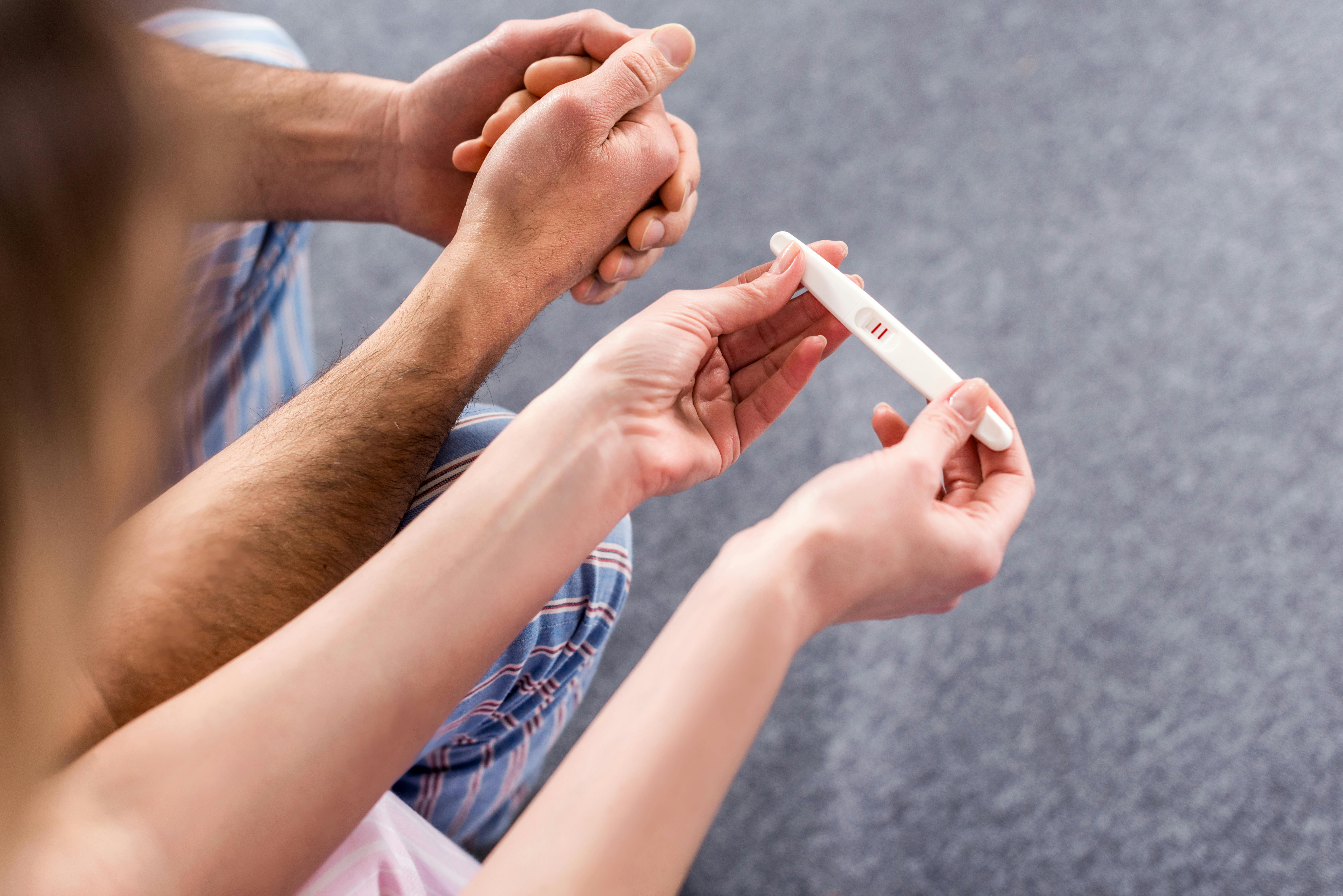 partial view of couple with pregnancy test