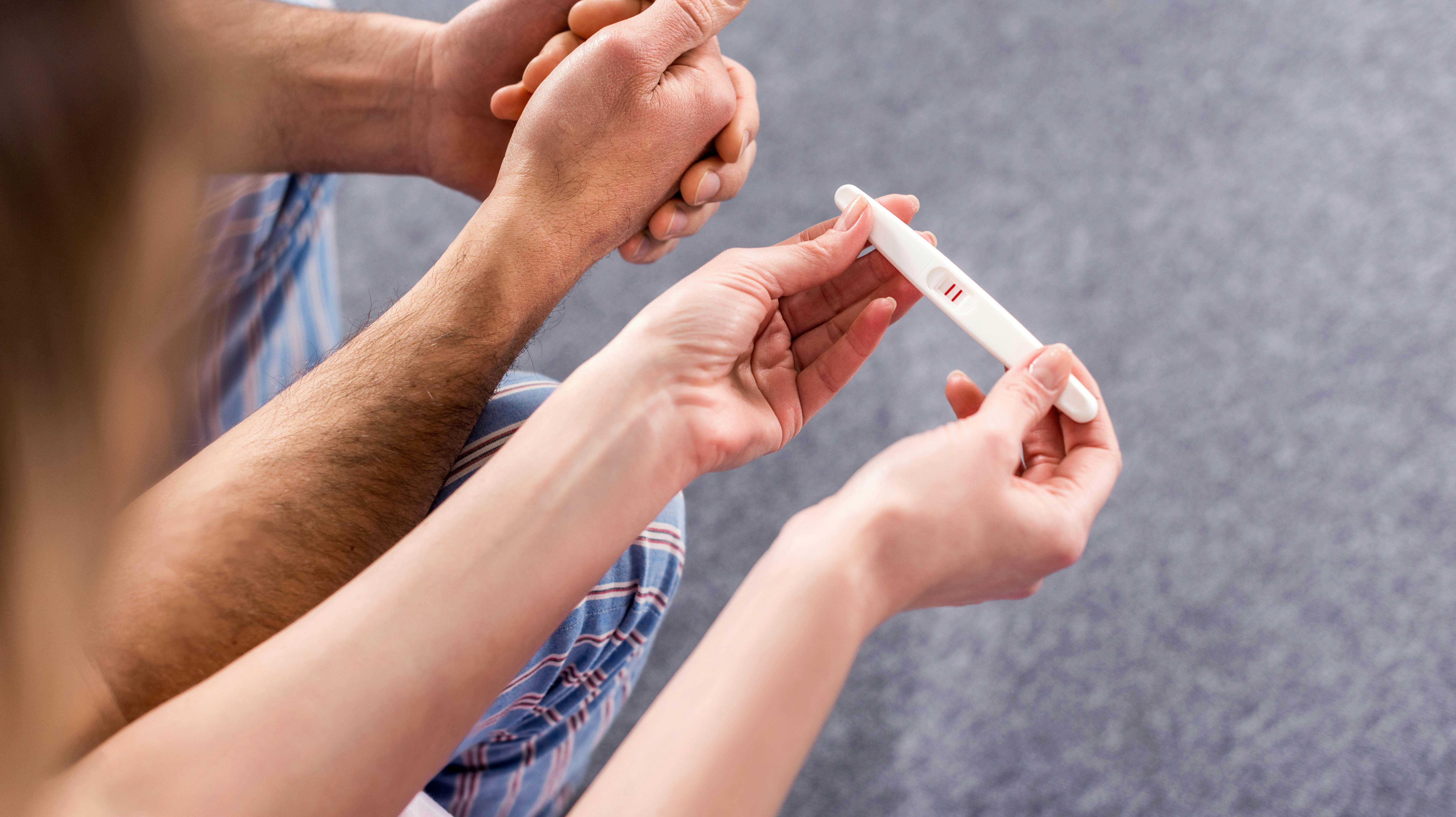 partial view of couple with pregnancy test
