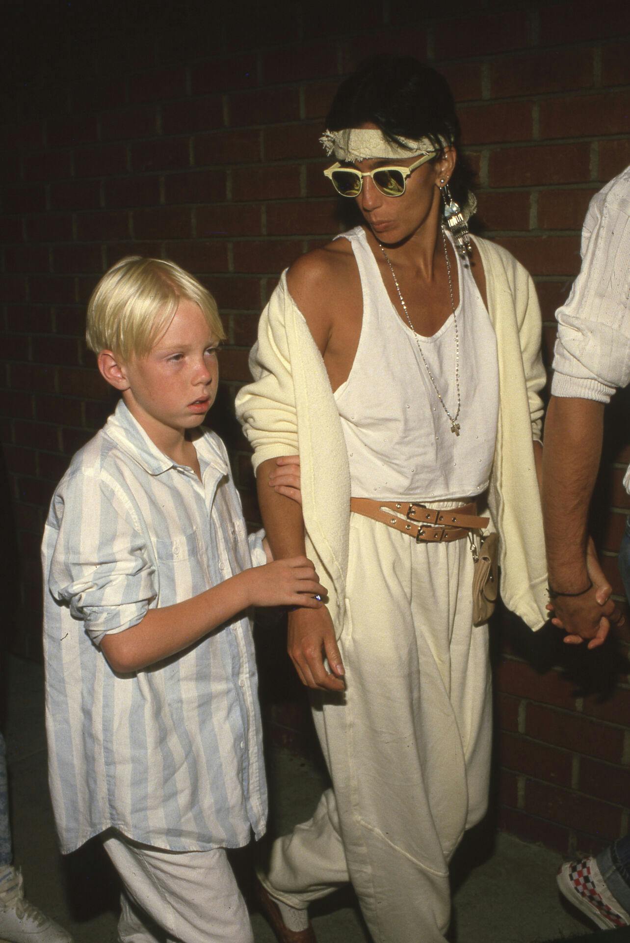 **FILE PHOTO** Cher Allegedly Hired 4 Men To Kidnap Son Elijah Blue Allman to prevent reconciliation with estranged wife. Cher and Elijah Blue 1986. Credit: Ralph Dominguez/MediaPunch /IPX