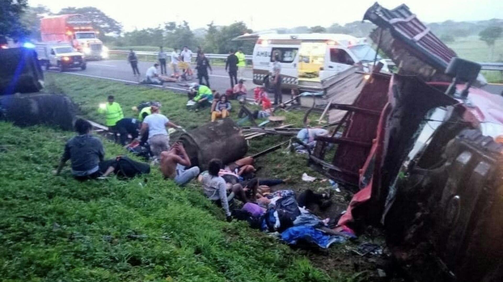 Overlevende følger chokeret med, mens redningsfolk kører væk med de døde, efter en lastbil søndag er væltet rundt med migranter i den sydlige mexicanske delstat Chiapas.