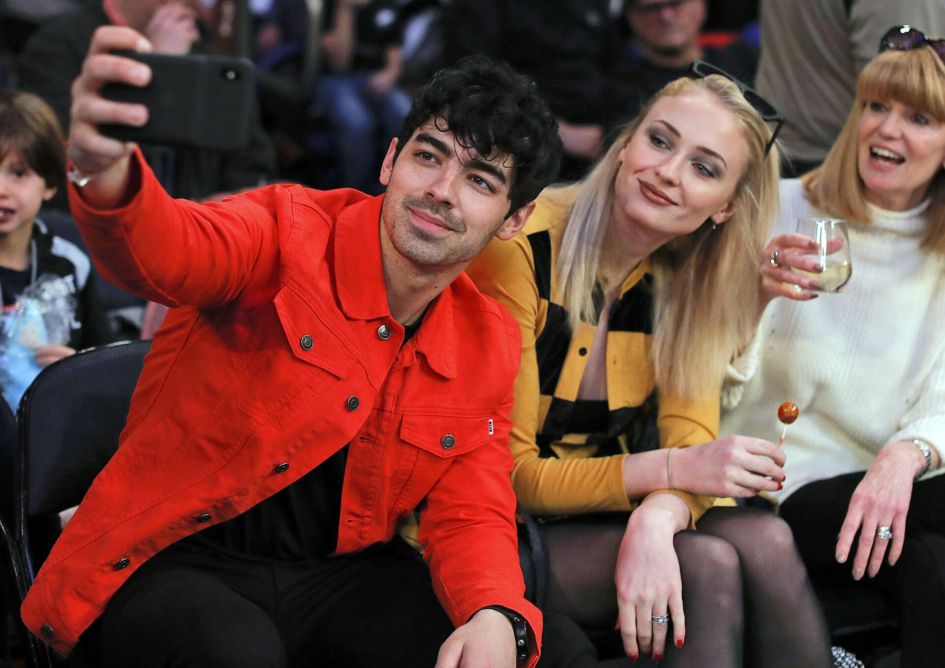 FILE Musician Joe Jonas, left, takes a selfie with actress Sophie Turner during a break in play of an NBA basketball game between the New York Knicks and the Sacramento Kings, Saturday, March 9, 2019, in New York. Turner sued her estranged pop star husband Jonas on Thursday, Sept. 21, 2023, to force him to turn over the passports of the couple's two young daughters so she can take them to England. (AP Photo/Julie Jacobson, File)