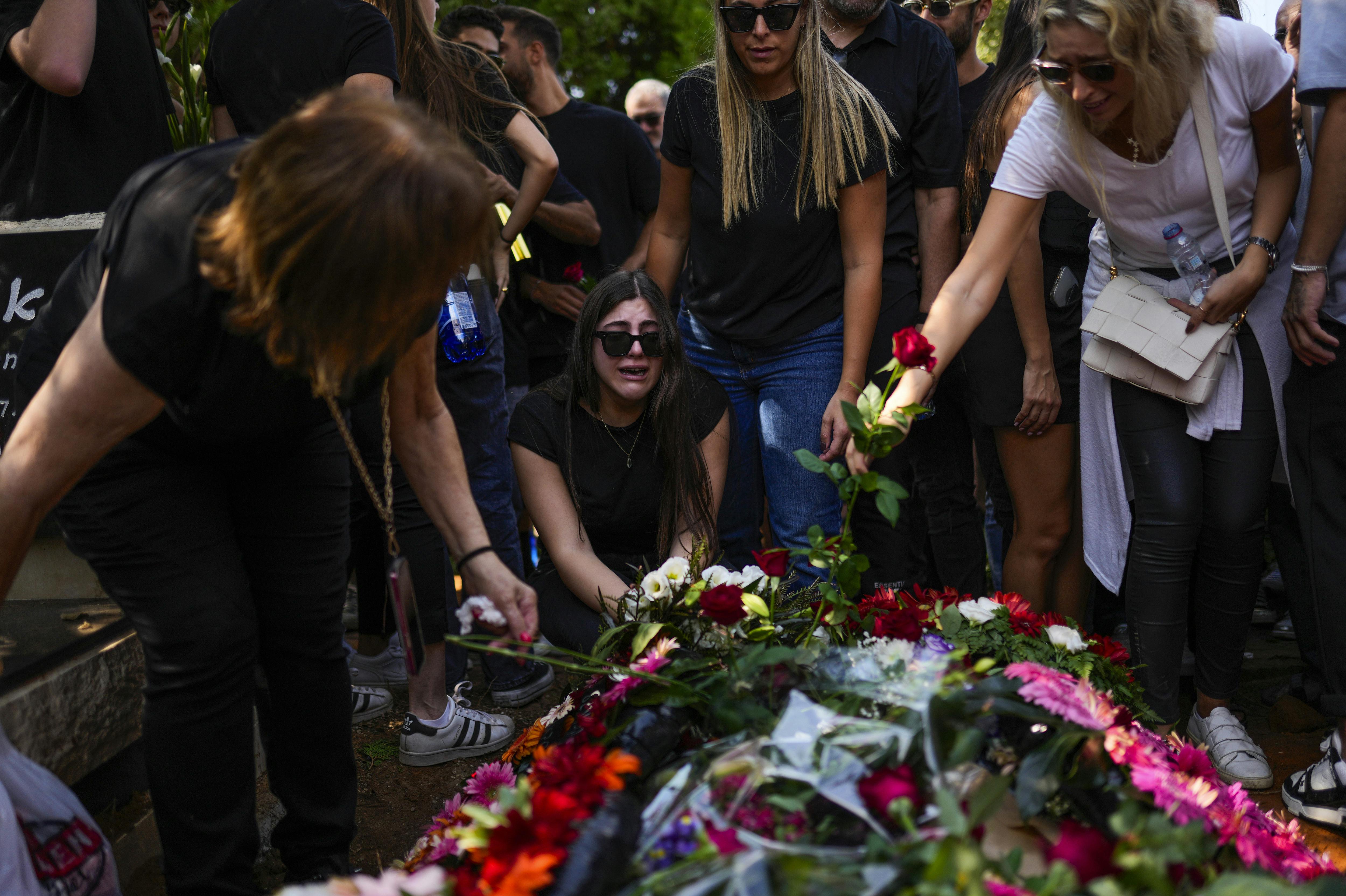 Mourners gather around the grave of May Naim, 24, during her funeral in Gan Haim, central Israel, Wednesday, Oct. 11, 2023. Naim and at least 260 more Israelis were killed by Hamas militants on Saturday at a rave near Kibbutz Re'im, close to the Gaza Strip's separation fence with Israel as the militant Hamas rulers of the territory carried out an unprecedented, multi-front attack that killed over 1, 000 Israelis. (AP Photo/Francisco Seco)