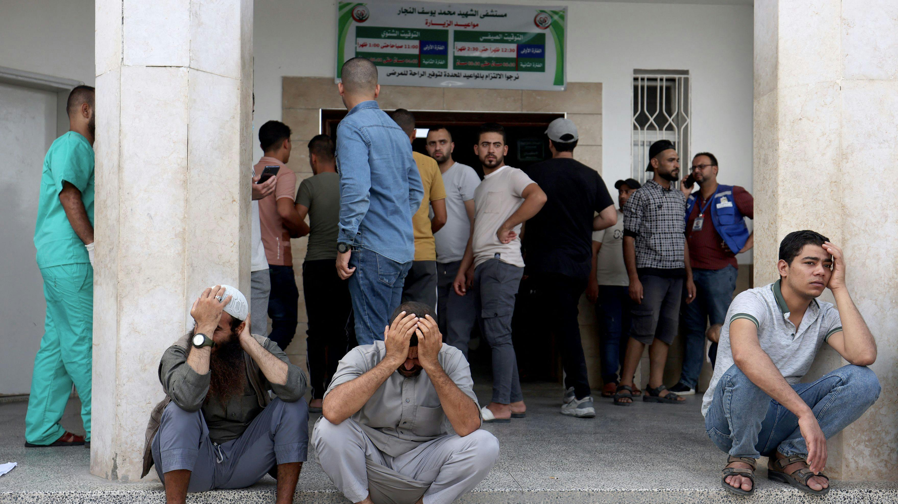 Palæstinensiske mænd sidder tynget af sorg ude foran et hospital i det sydlige Gaza den 17. oktober. Her har et israelsk luftangreb ramt hospitalet i Rafah.