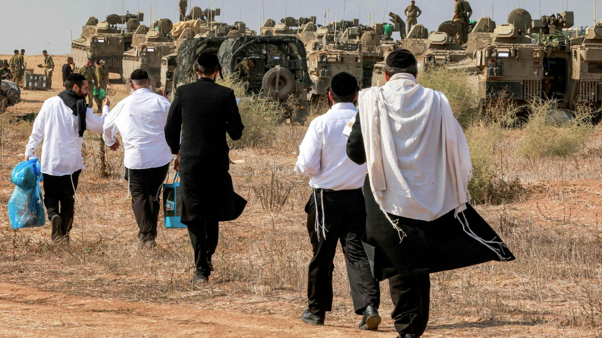 (FILES) Ultra-Orthodox Jews visit Israeli army soldiers to show their support as they deploy at a position near the border with Gaza in southern Israel on October 11, 2023. (Photo by Menahem KAHANA / AFP)