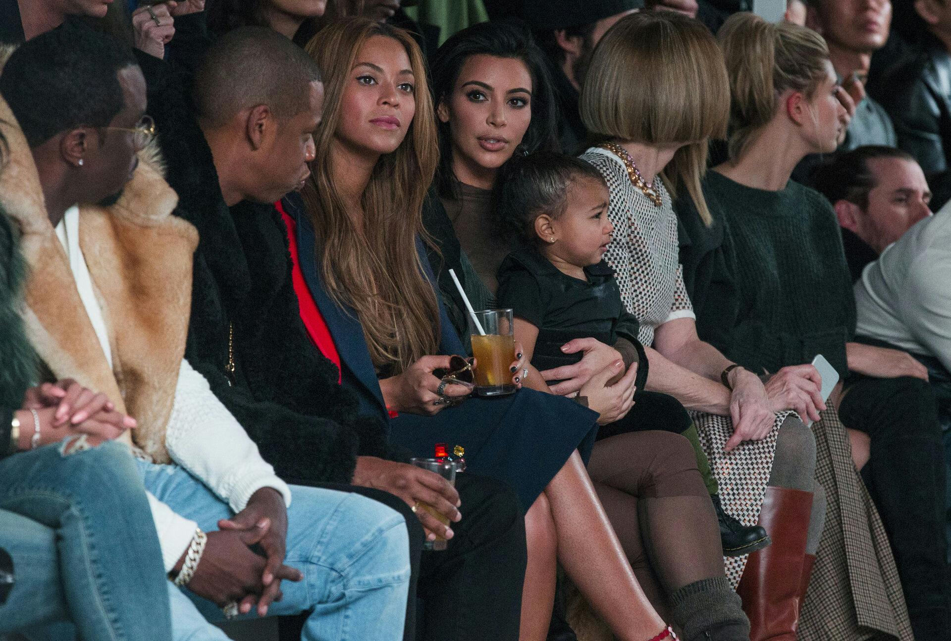 Kim Kardashian med lille North West i armene og ved siden af Beyoncé og Jay-Z (tv.) og Vogue-boss Anna Wintour (th.) i forbindelse med Kanye Wests Adidas-modeshow i 2015.