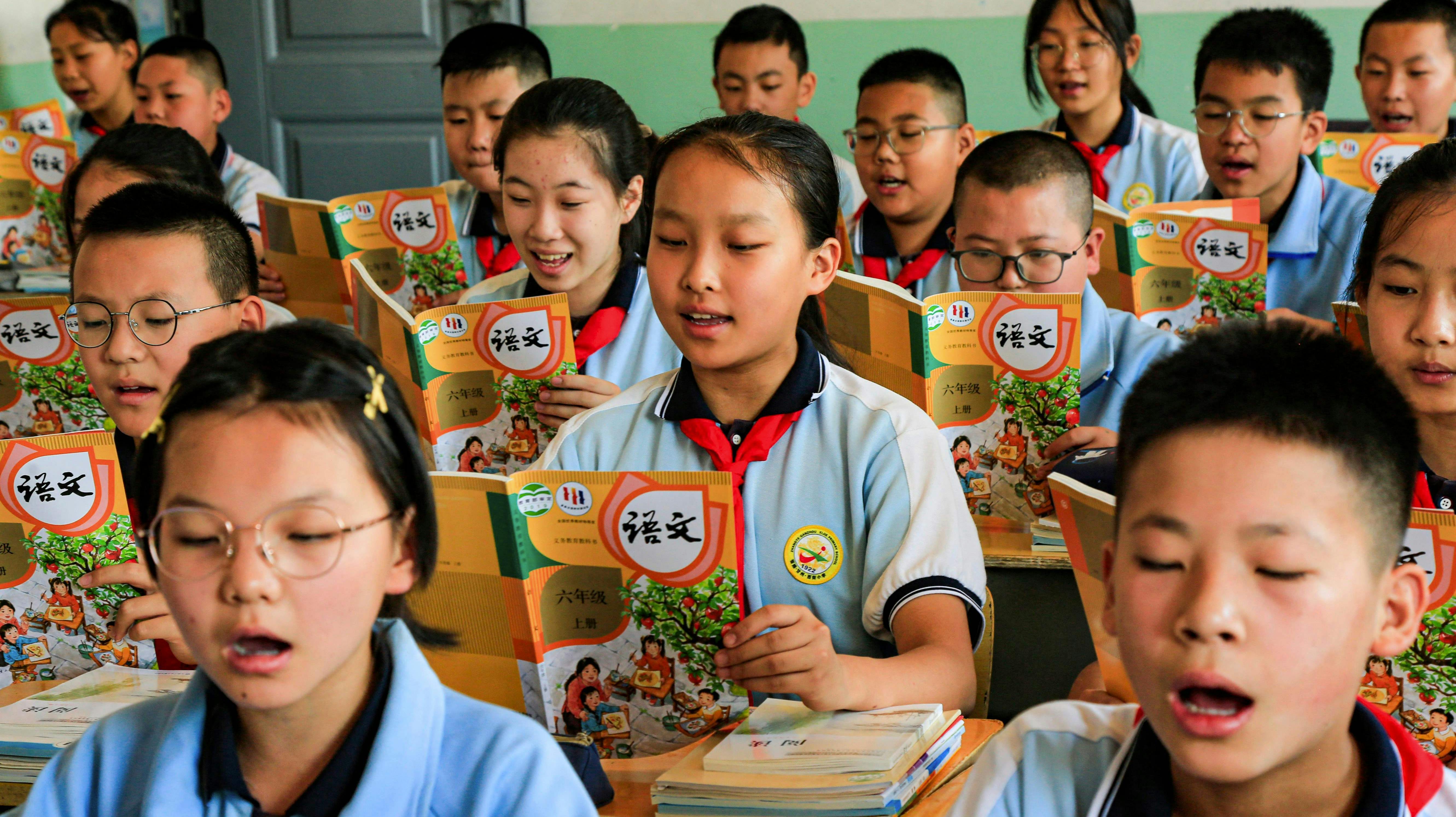 In this photo taken on August 28, 2023, students read from newly-issued text books at a primary school in Zhangye city, in China's northwest Gansu Province. (Photo by AFP) / China OUT