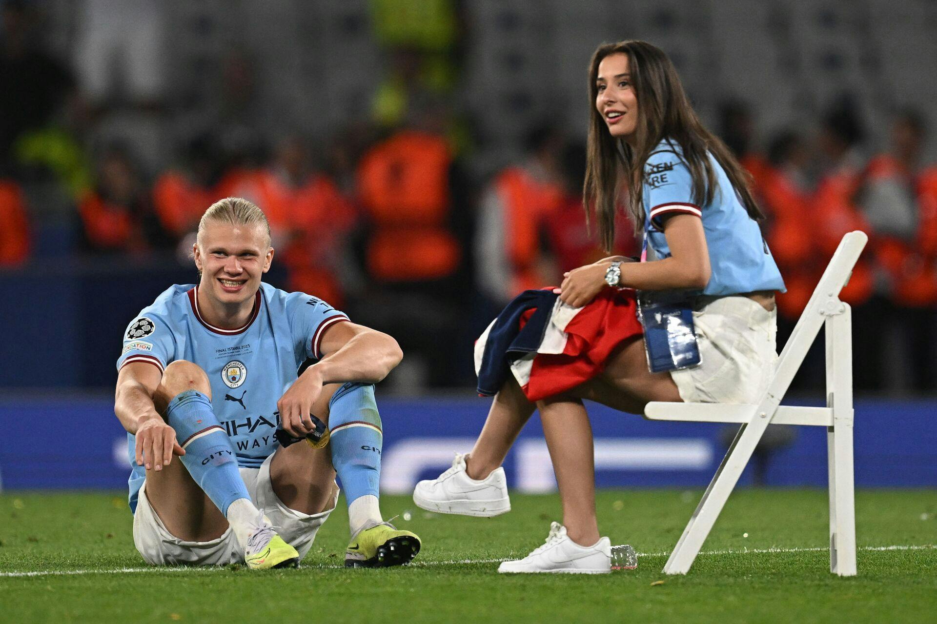 Manchester City's Norwegian striker #9 Erling Haaland and his girlfriend Isabel Johansen sit on the pitch as he celebrates winning the UEFA Champions League final football match between Inter Milan and Manchester City at the Ataturk Olympic Stadium in Istanbul, on June 10, 2023. Manchester City won the match 1-0. (Photo by Paul ELLIS / AFP)