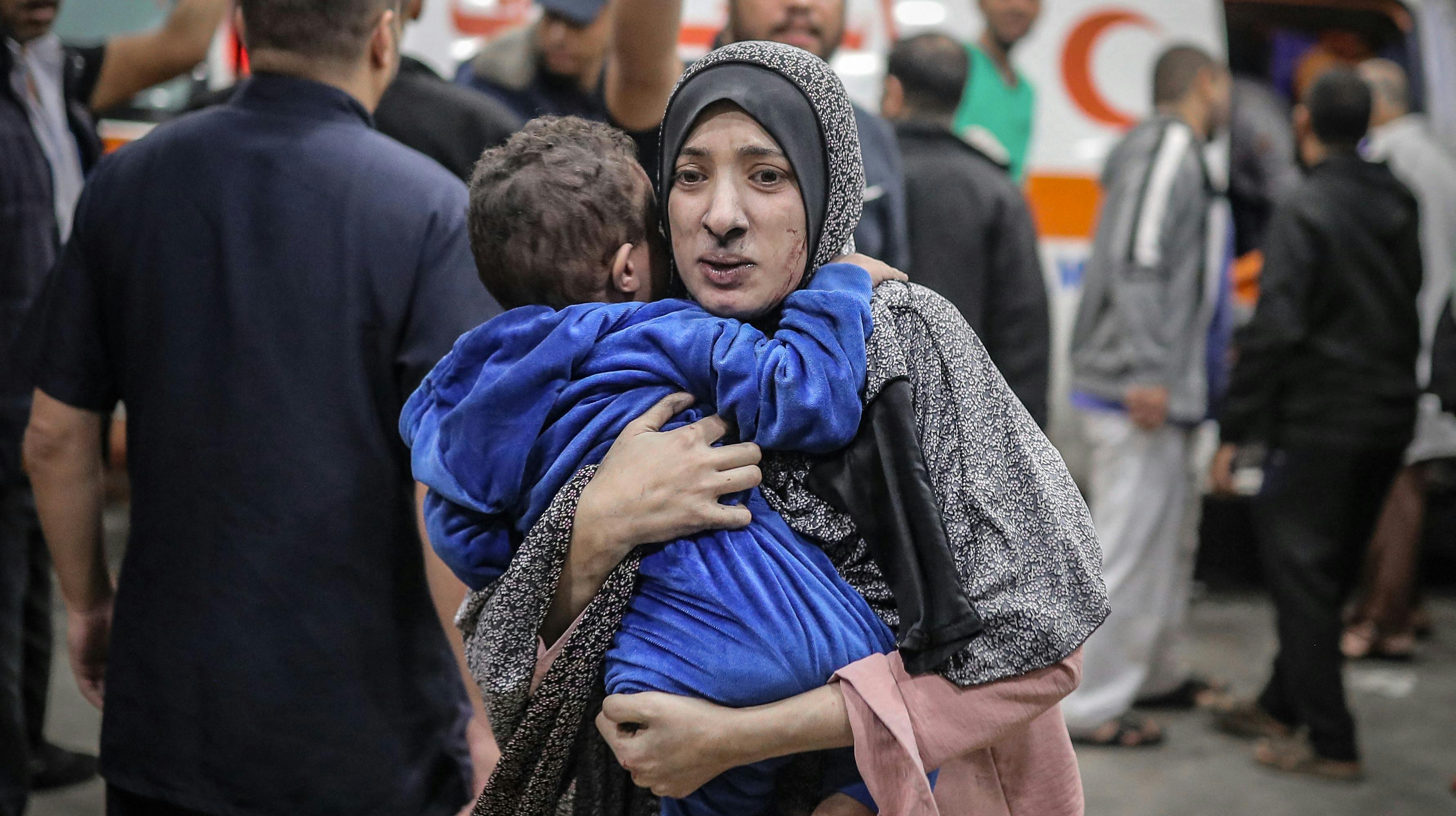 En palæstinensisk kvinde bærer sit sårede barn til et hospital efter bombeangrebet på byen Khan Yunis i det sydlige Gaza